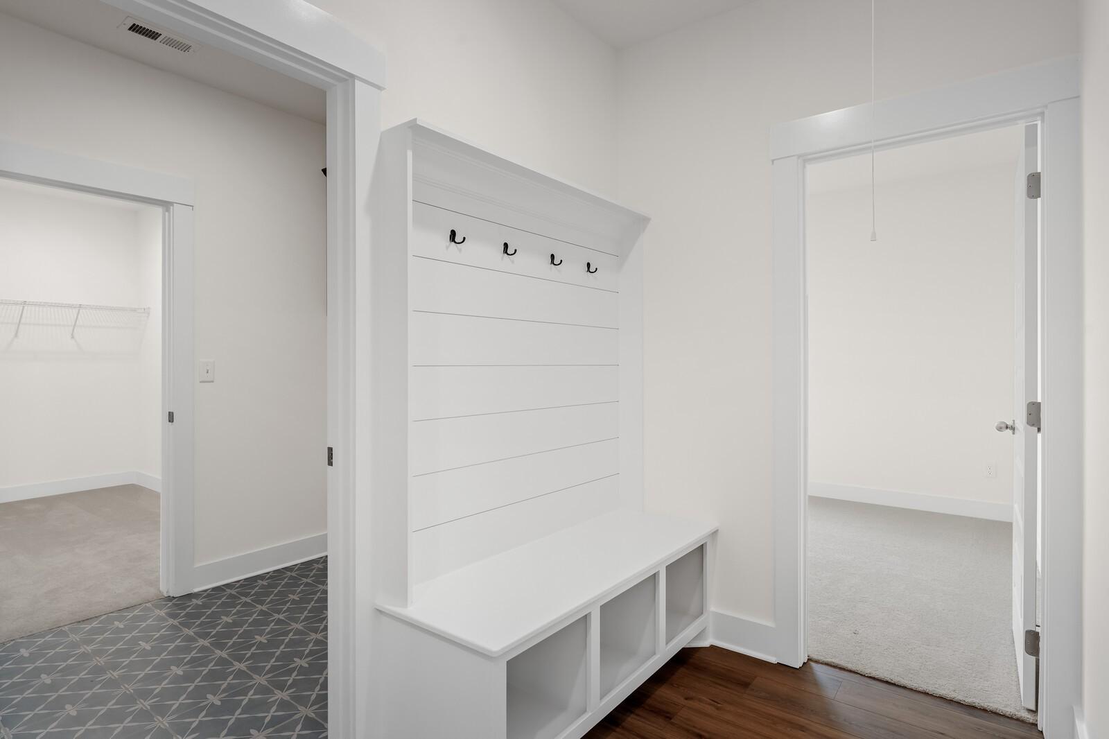 Built-in white mudroom bench with coat hooks in The Prairie C floor plan at Woods Crossing, Gallatin, Tennessee.