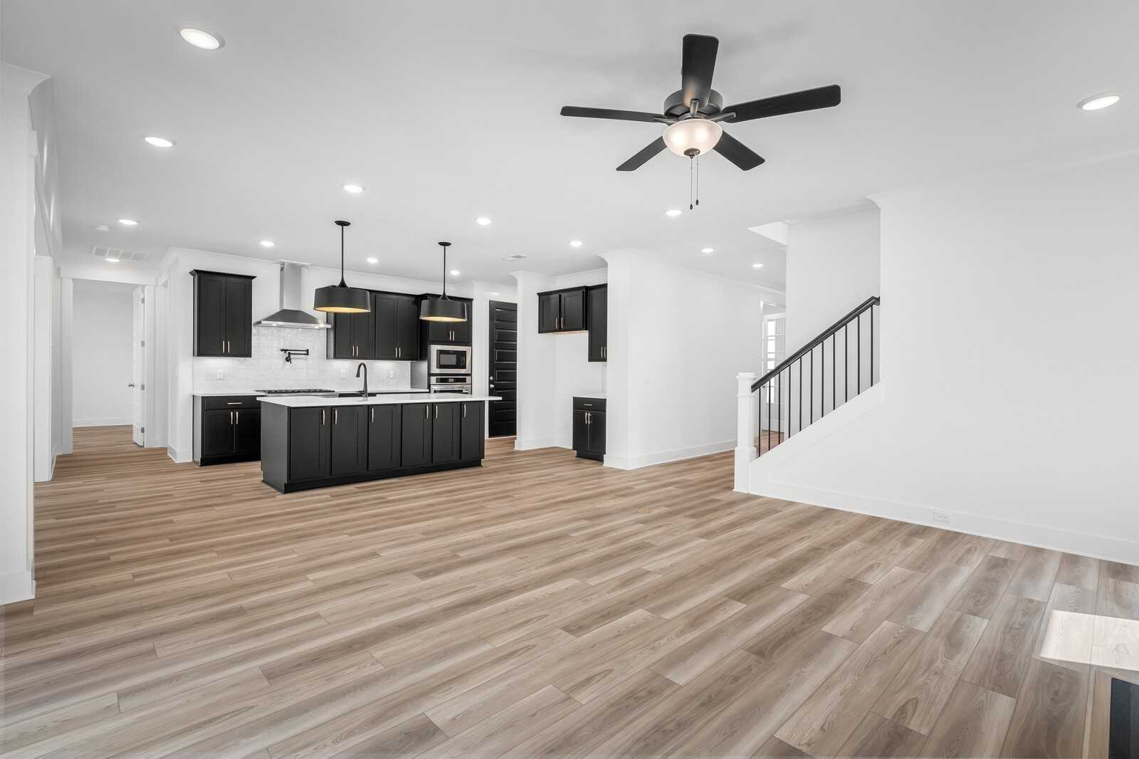 Open-concept kitchen with black cabinets, large island, stainless appliances, and hardwood floors in Davidson Homes The Hathaway, Murfreesboro, TN