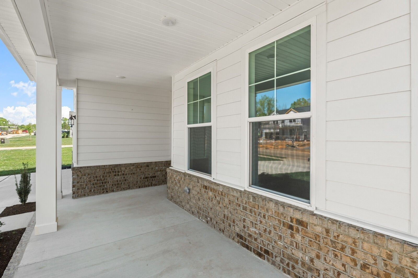 Covered front porch with white siding and brick accents on The Henry C floor plan in Calista Farms, White House, Tennessee.