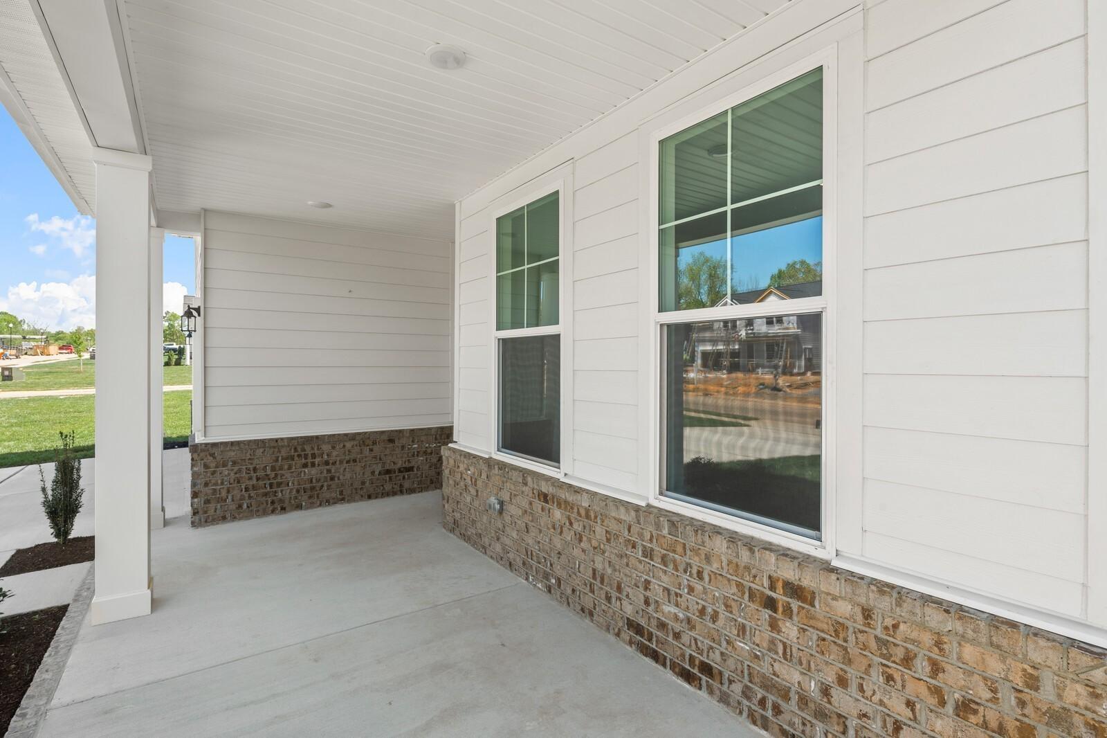 Covered front porch with white siding and brick accents on The Henry C floor plan in Calista Farms, White House, Tennessee.