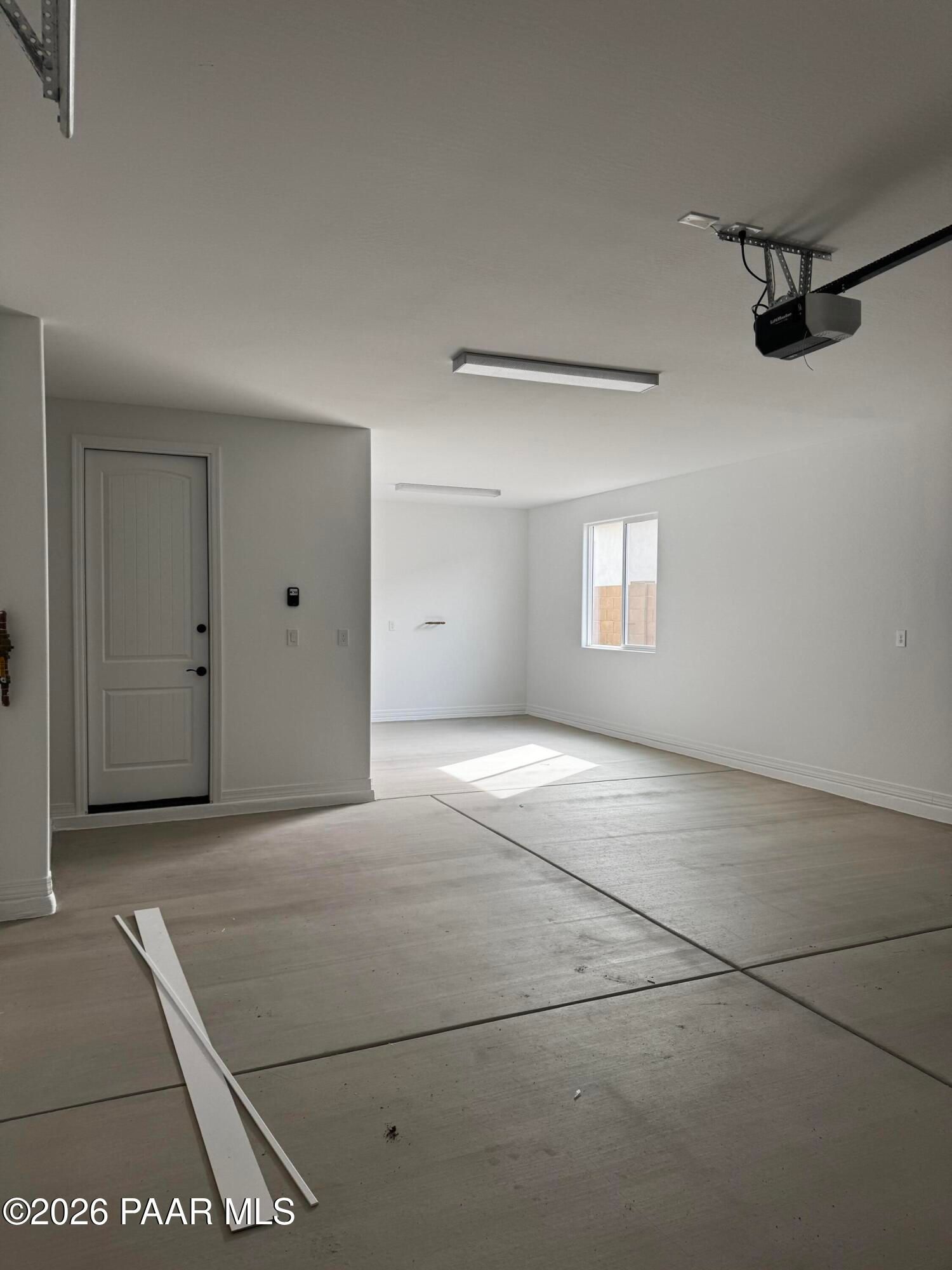 Spacious 3-car garage with concrete floor, white walls, overhead door in The Durango II B by Davidson Homes, Prescott, AZ