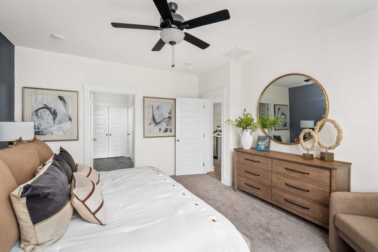 Spacious master bedroom at Woods Crossing in Gallatin TN with king bed, wood dresser, gold mirror, abstract art