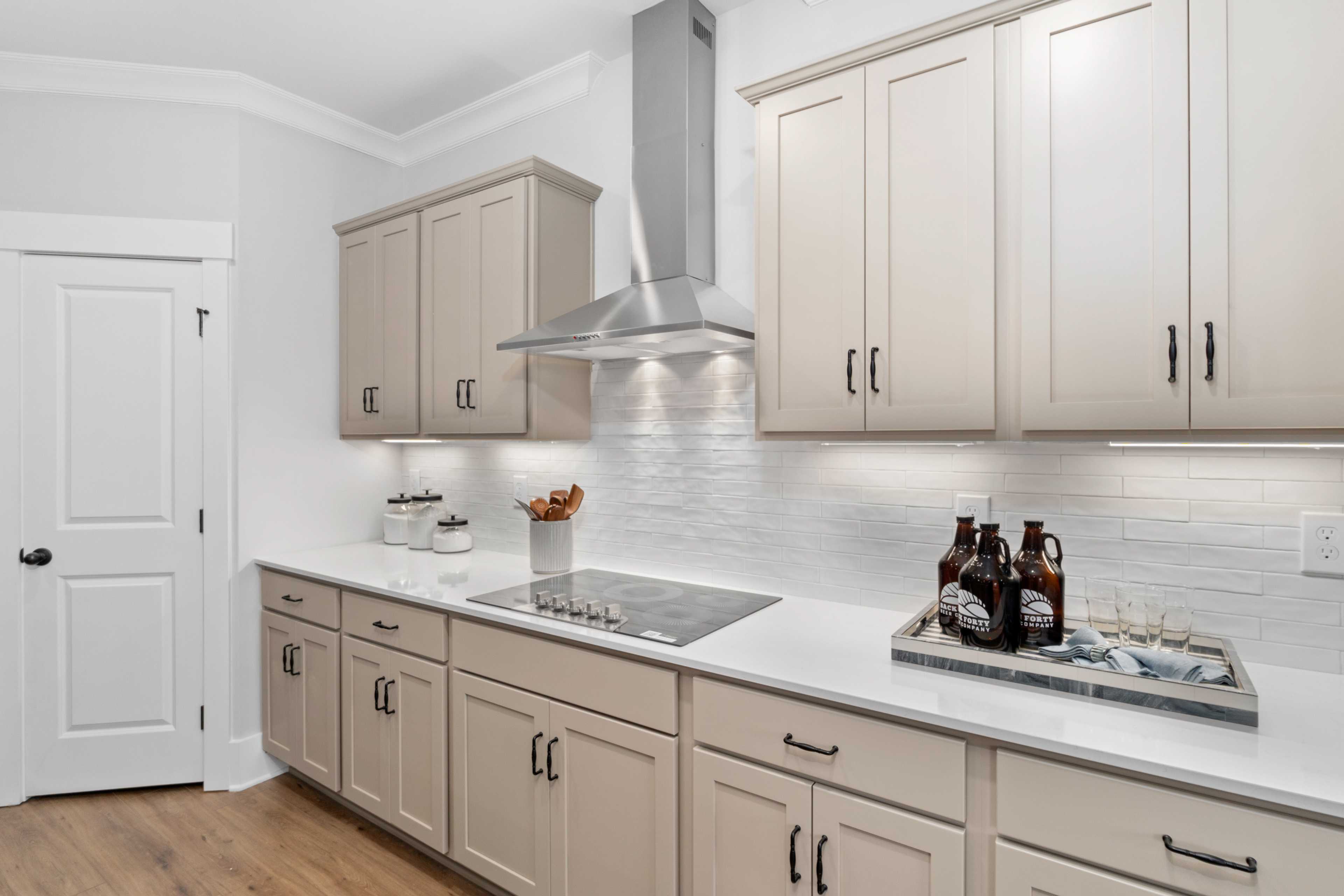 Spacious modern kitchen at Kendall Farms in Toney, Alabama by Davidson Homes with beige shaker cabinets, island cooktop, and subway tile backsplash