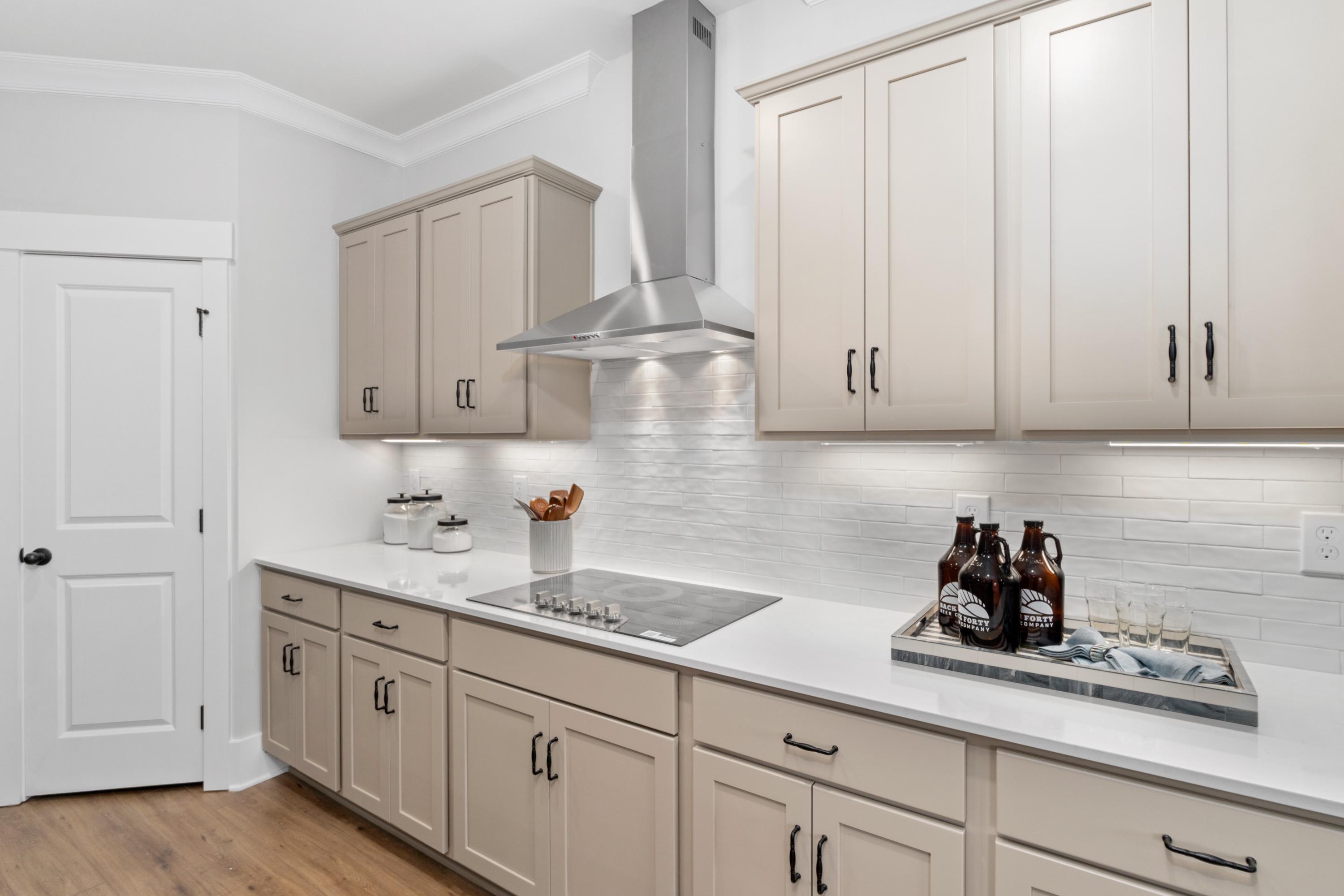 Spacious modern kitchen at Kendall Farms in Toney, Alabama by Davidson Homes with beige shaker cabinets, island cooktop, and subway tile backsplash