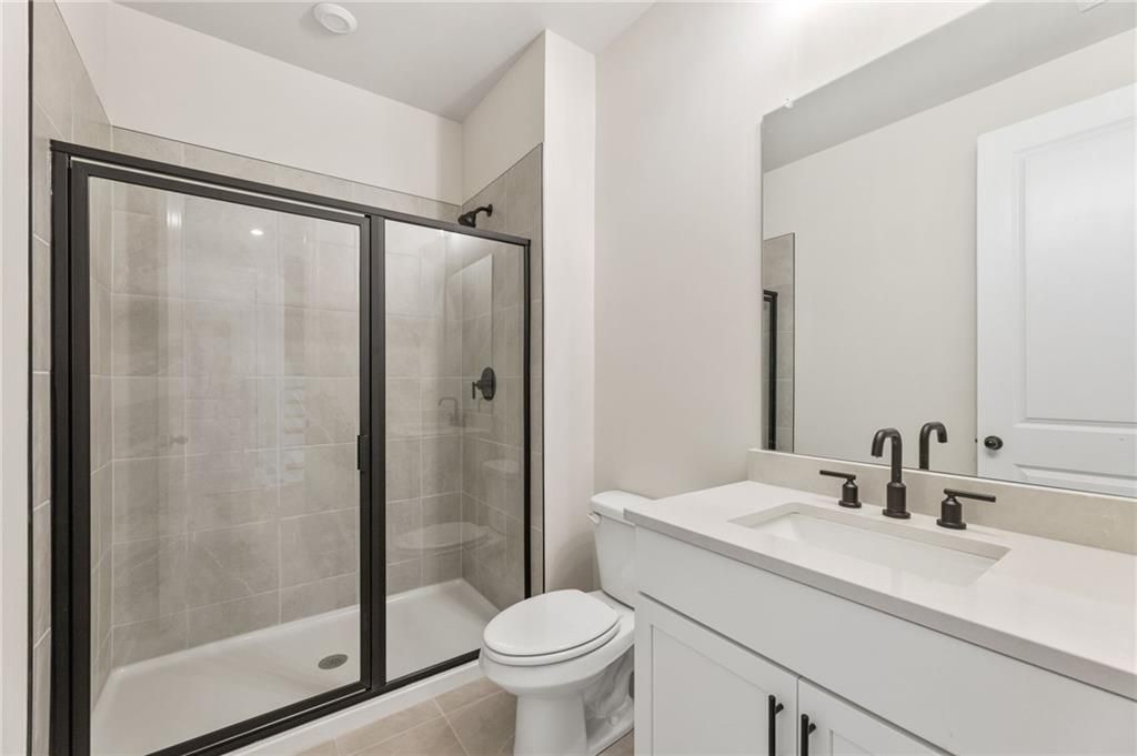 Modern bathroom featuring frameless glass shower, double white vanity, subway tile in The Hickory B, Buford, GA