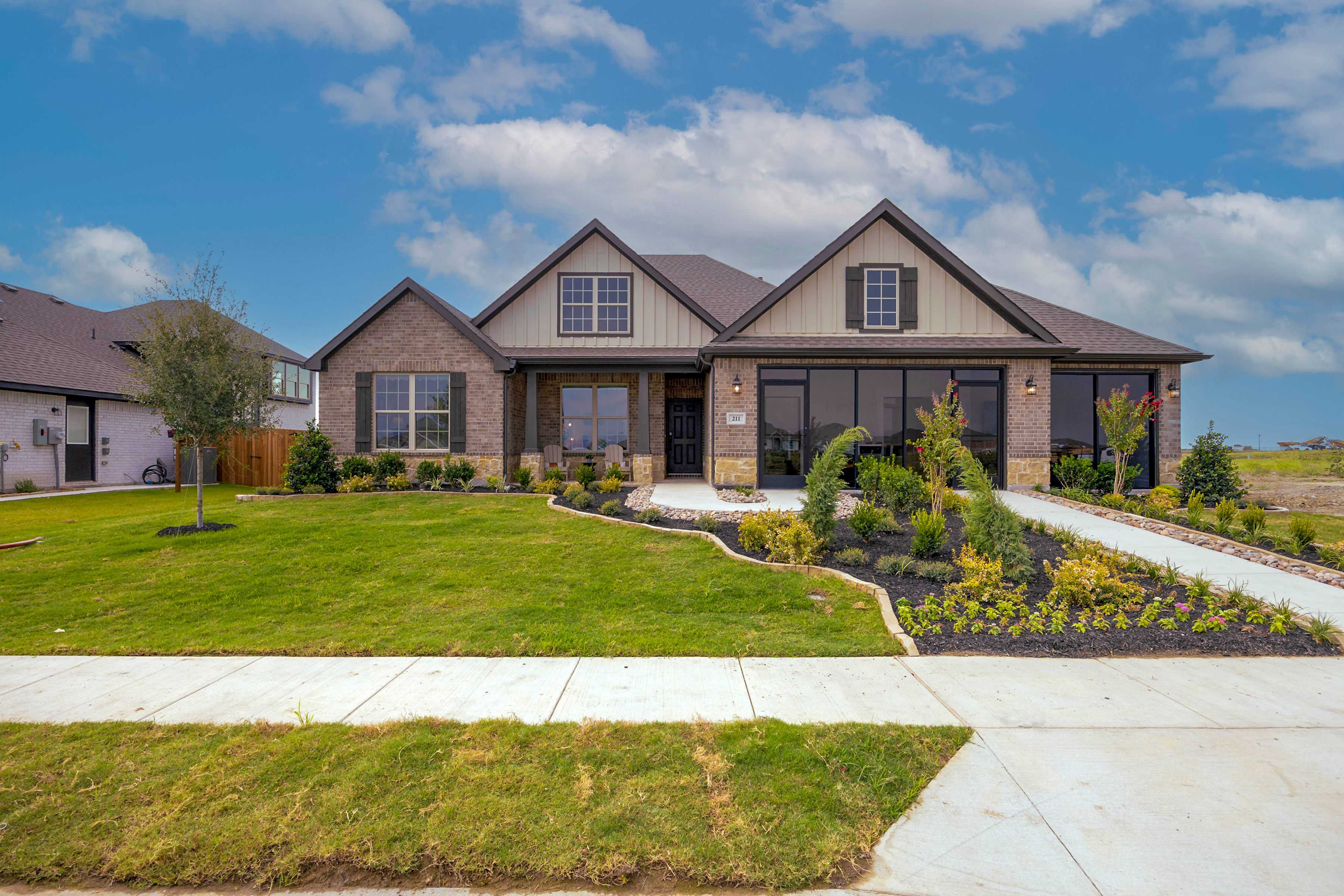 Modern brick home exterior at Waverly Estates in Josephine Texas with gabled roof large windows and landscaped front yard