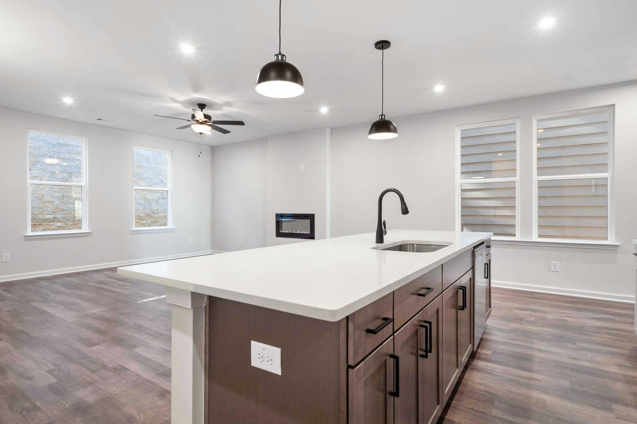 Open-concept kitchen in The Cary B Davidson Homes with large white island, black cabinets, pendant lights, and ceiling fan