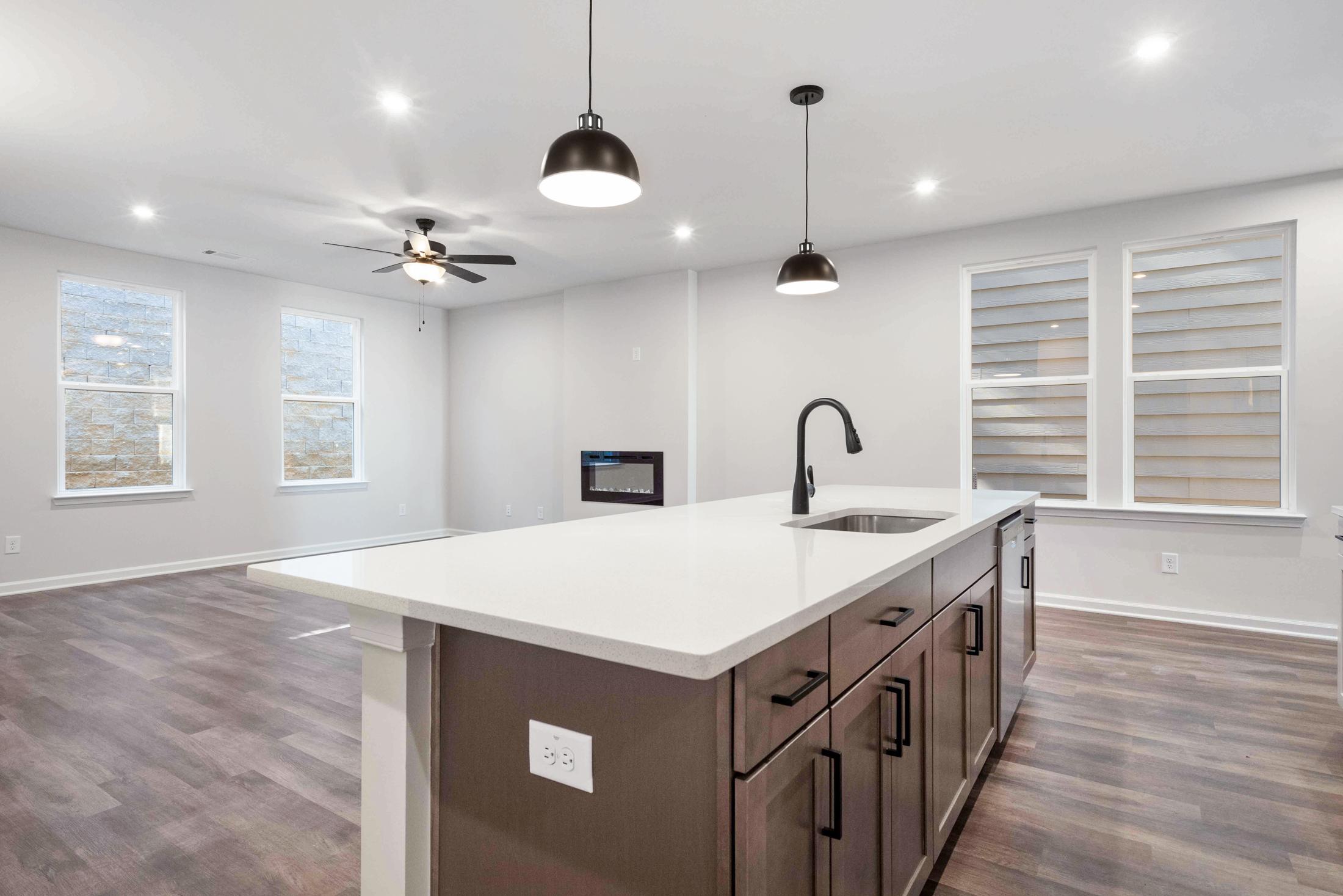 Open-concept kitchen in The Cary B Davidson Homes with large white island, black cabinets, pendant lights, and ceiling fan