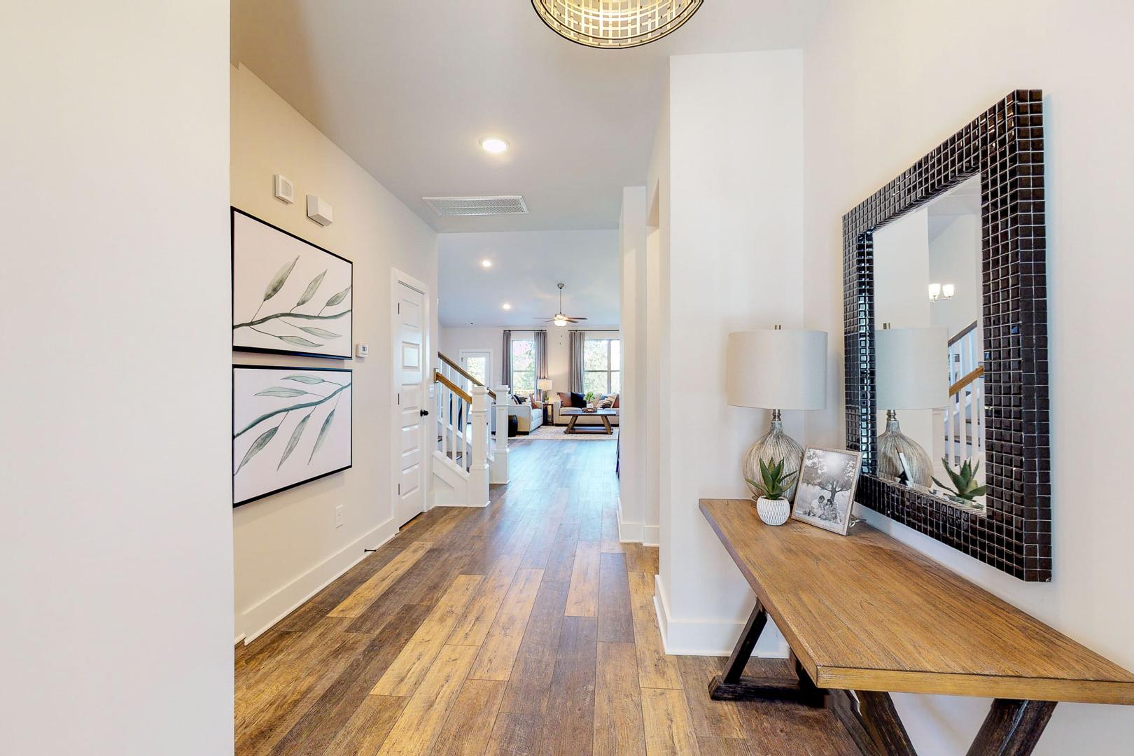 Elegant entry hallway at Liberty Creek in Gallatin TN with hardwood floors, wooden console table, lamp, and large mirror