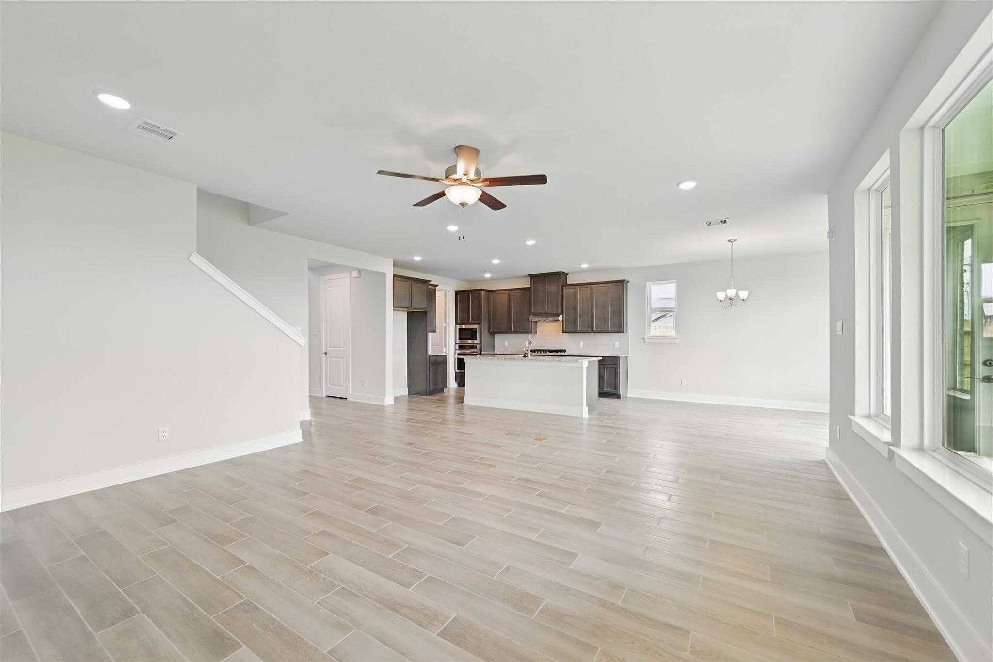 Open-concept kitchen and living space with large island, wood cabinets, and staircase in Davidson Homes The Philip A, Lago Mar