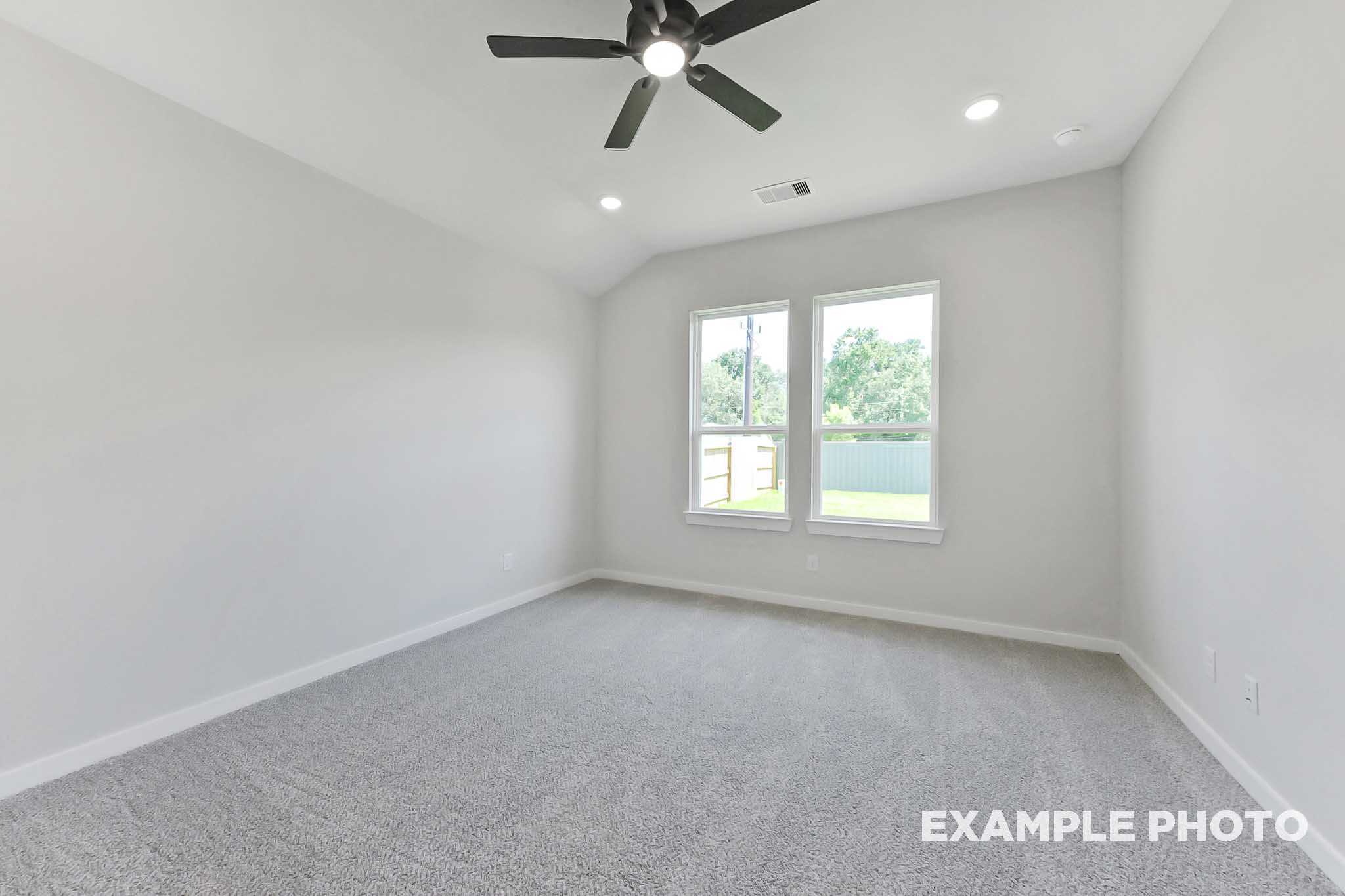 Bright secondary bedroom in The Sequoia with gray carpet, ceiling fan, recessed lights, and dual windows overlooking green yard