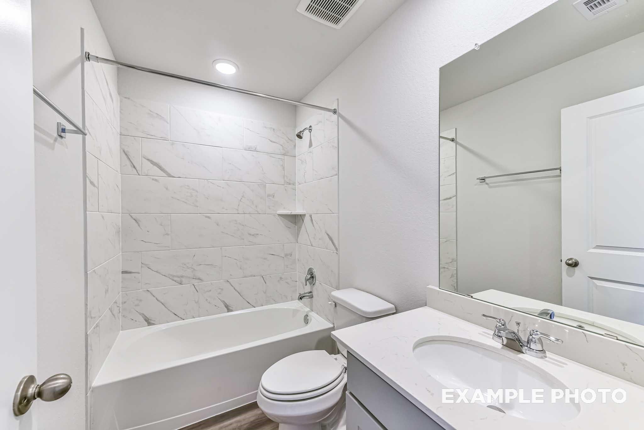 Modern bathroom with marble-look tub surround and vanity in The Laguna C floor plan by Davidson Homes in Sunterra, Katy.