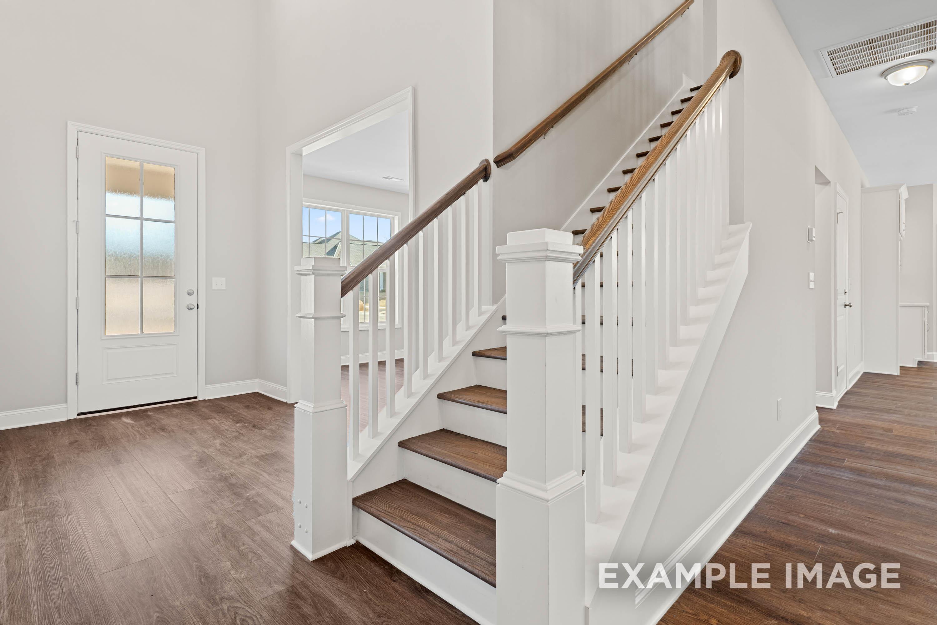 Grand staircase in The Madison B 2-story home by Davidson Homes, white balusters, wood treads, open foyer, hardwood floors