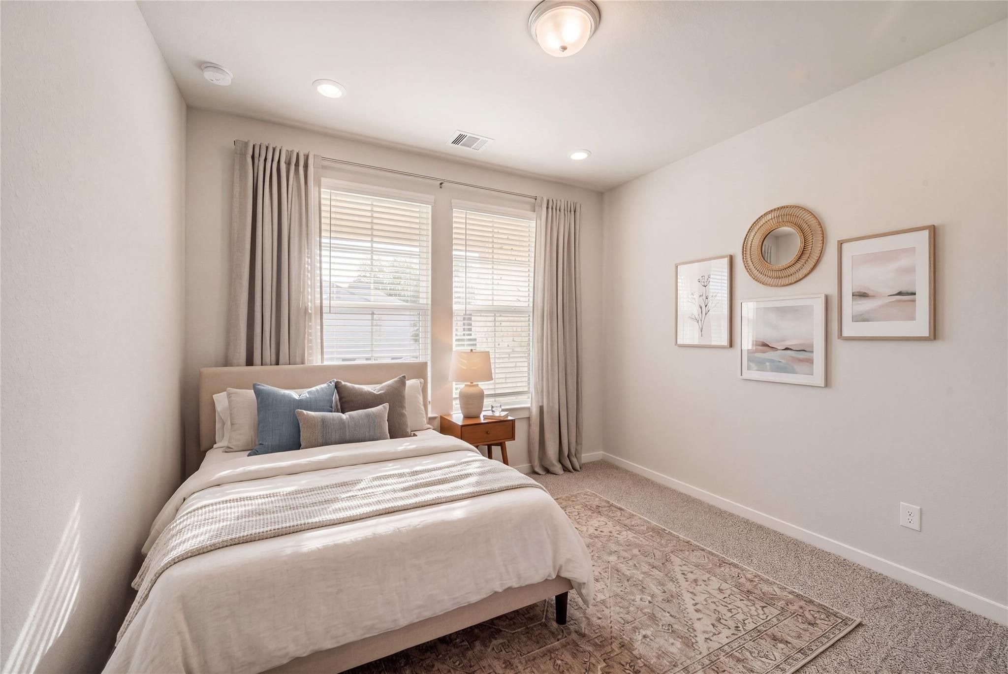 Cozy secondary bedroom with queen bed, neutral linens, sheer curtains on large windows, wall art in Davidson Homes The Acadia C, Magnolia, Texas