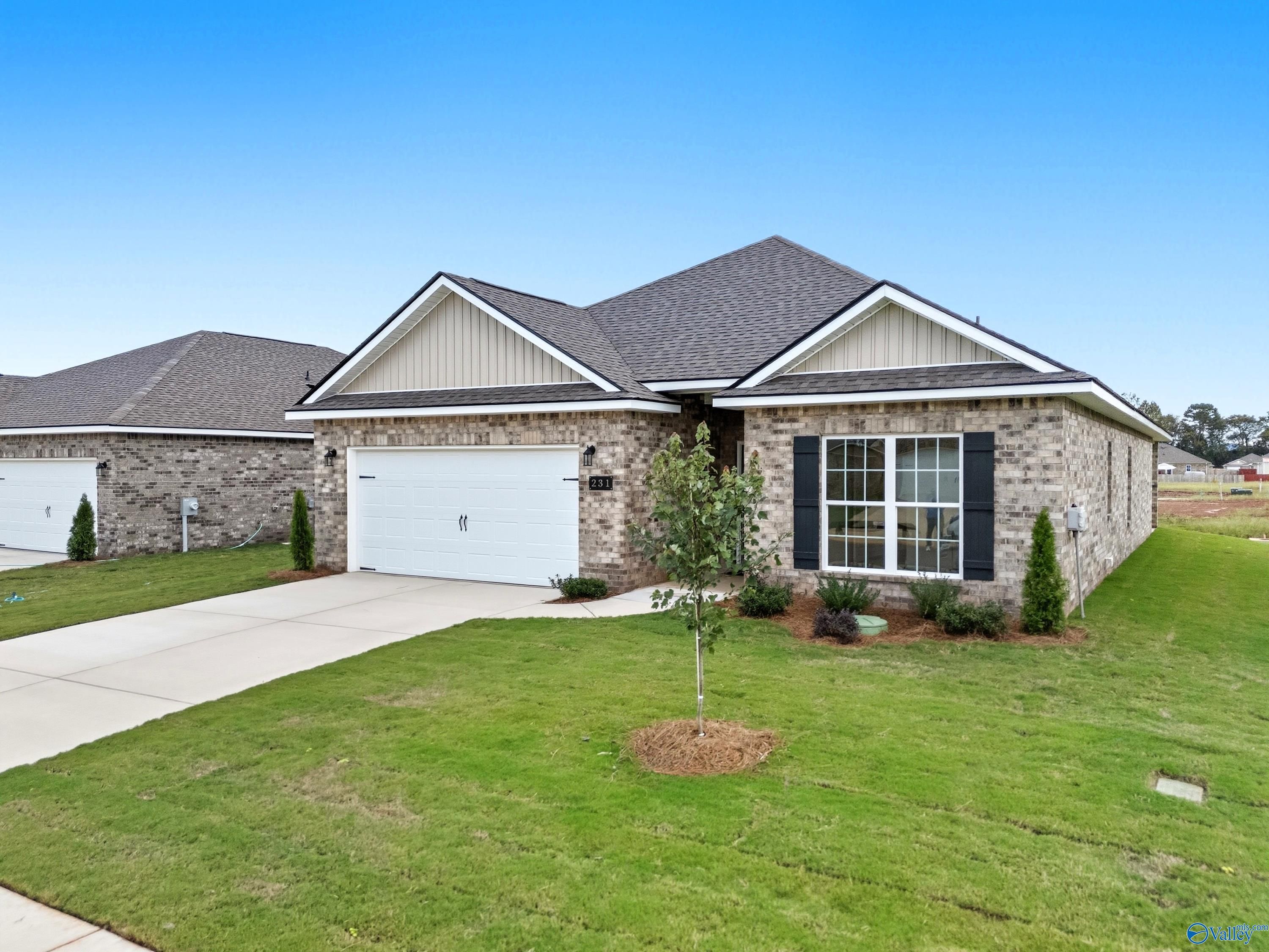 Modern 1-story brick home with 2-car garage, driveway, and lush green lawn in Lynn Meadows, Meridianville, Alabama - Davidson Homes Everett