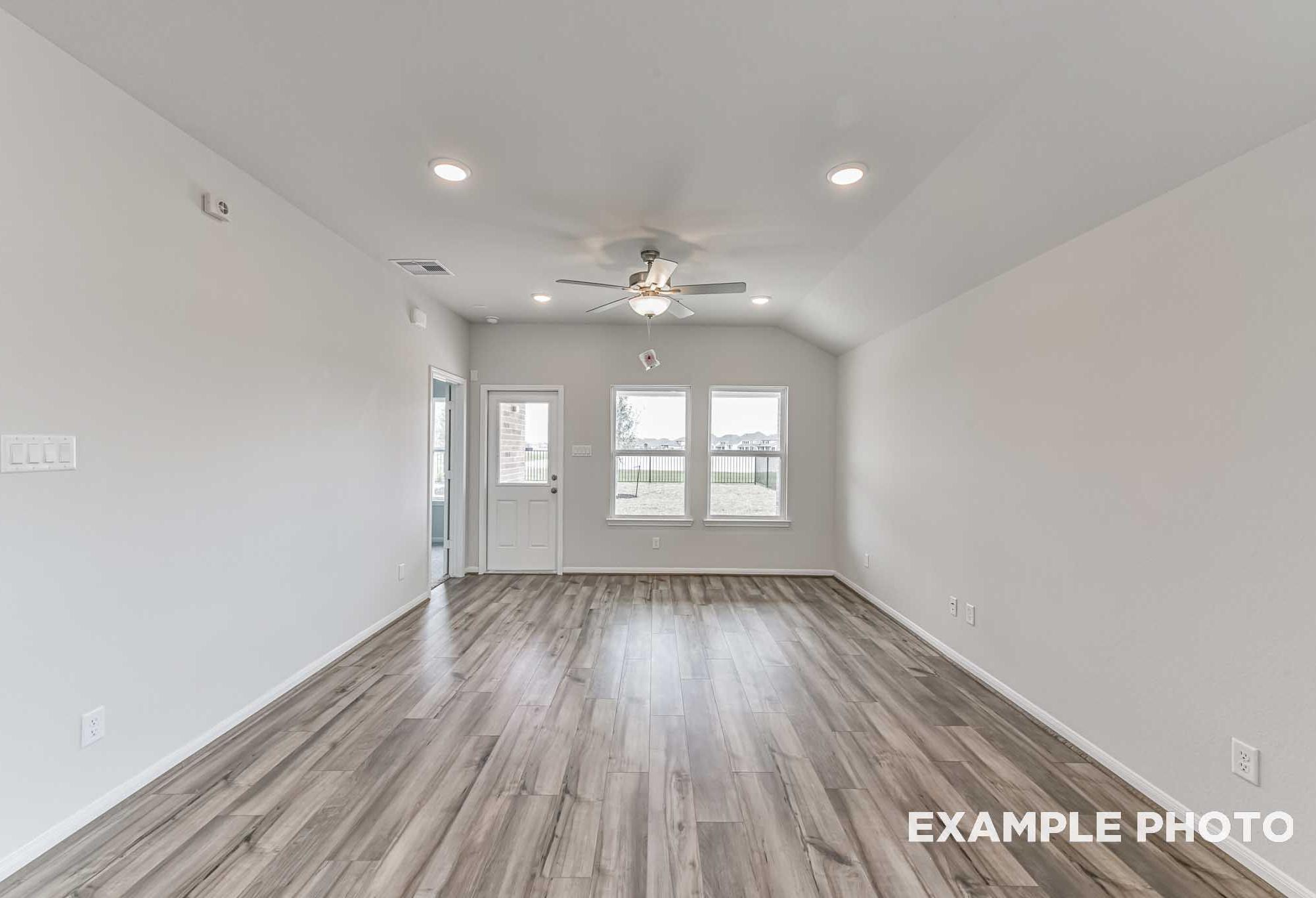 Bright open-concept living area in The Azure by Davidson Homes with vinyl plank flooring, ceiling fan, and backyard windows.