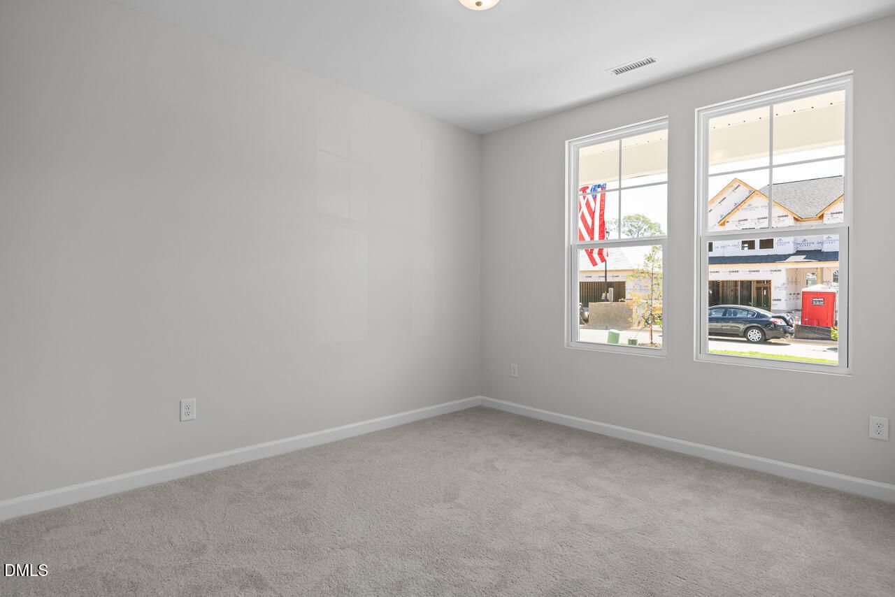 Bright carpeted bedroom with white walls and double windows in Davidson Homes' The Daphne D at Woodland Crossing, Zebulon NC