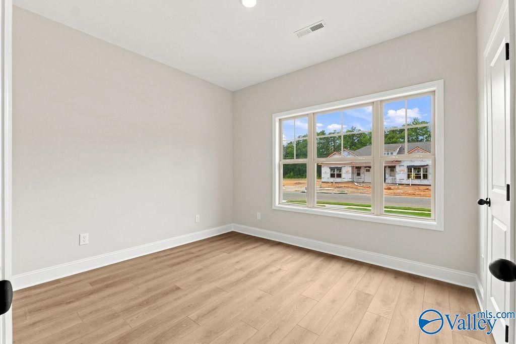Bright bedroom with wood-look flooring and large windows in The Camilla C floor plan at The Retreat at Cain Park, Hartselle.