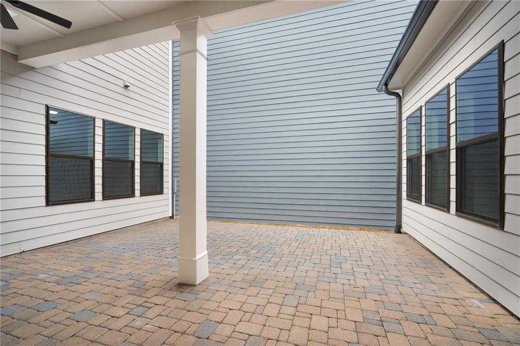 Covered paver patio with white columns and ceiling fans, adjacent to screened windows in Davidson Homes The Seaside B, Woodstock, Georgia