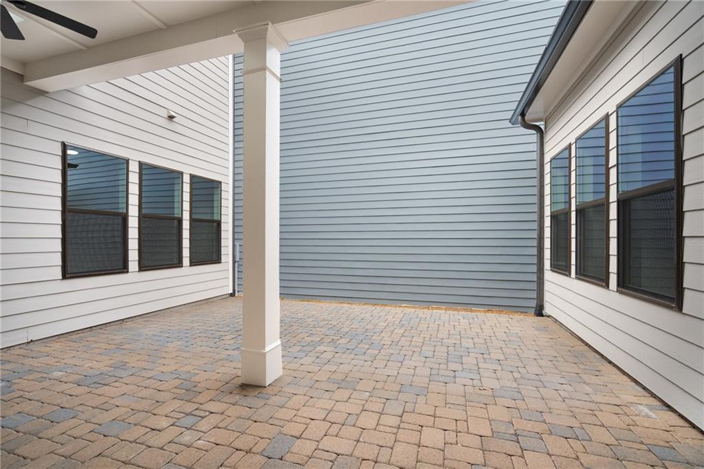 Covered paver patio with white columns and ceiling fans, adjacent to screened windows in Davidson Homes The Seaside B, Woodstock, Georgia