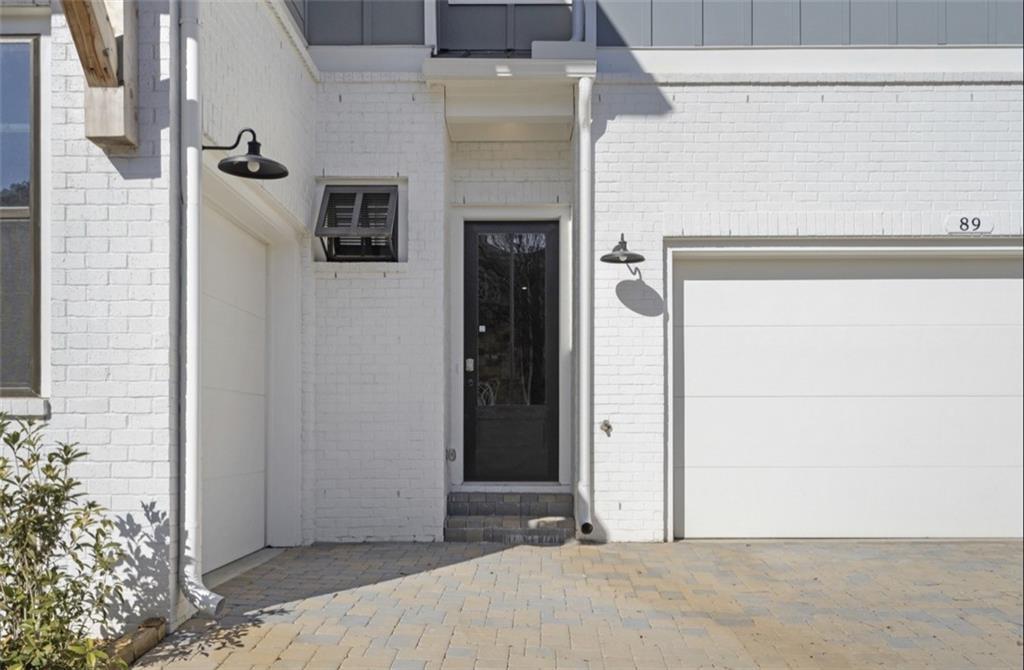 White brick facade with black front door, white garage, lanterns and pavers in Davidson Homes Seaside A, Woodstock GA