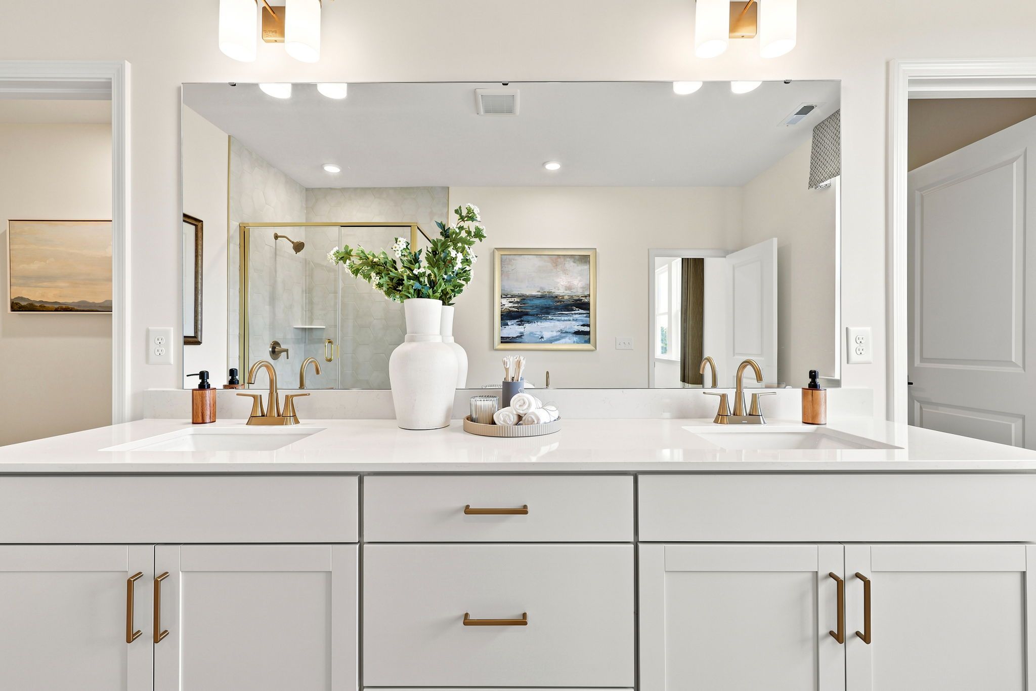 Modern master bathroom vanity in The Beech B featuring dual sinks, white cabinetry, and elegant gold hardware.