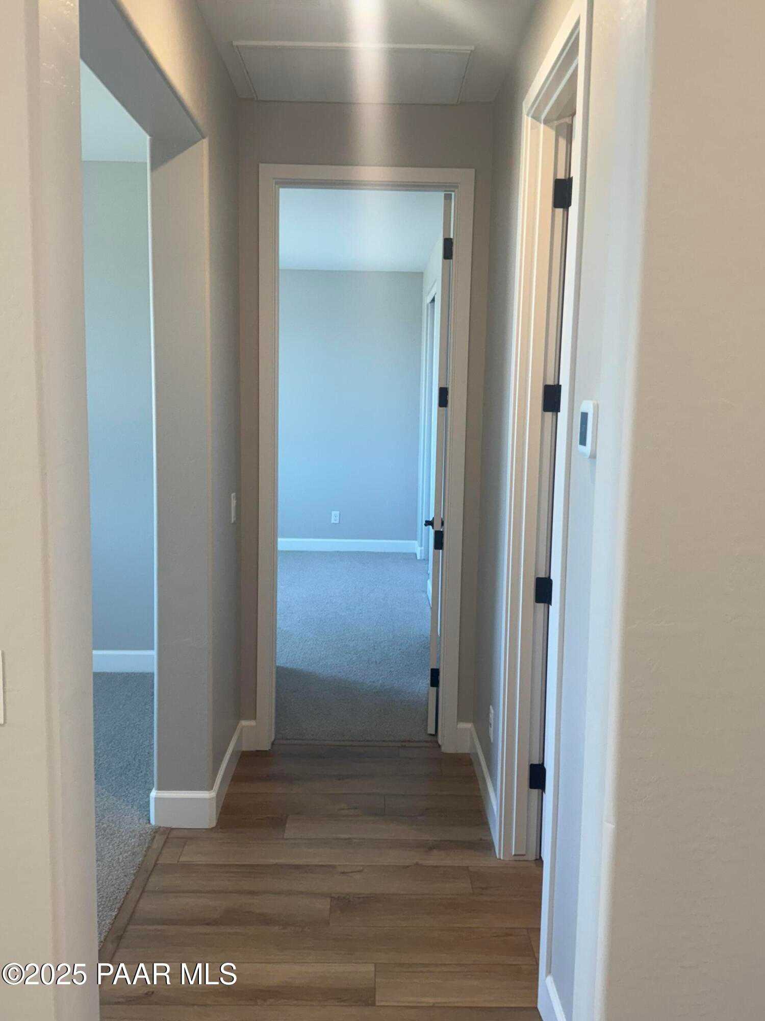 Wide hallway with arched doorways, neutral walls, and hardwood flooring in Evermore Homes The Summit B, Prescott Valley, AZ