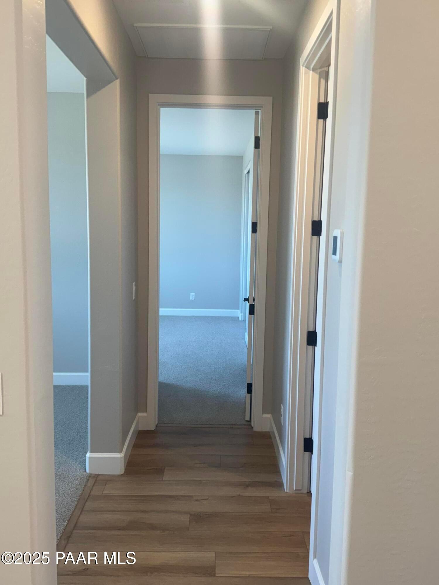 Wide hallway with arched doorways, neutral walls, and hardwood flooring in Evermore Homes The Summit B, Prescott Valley, AZ