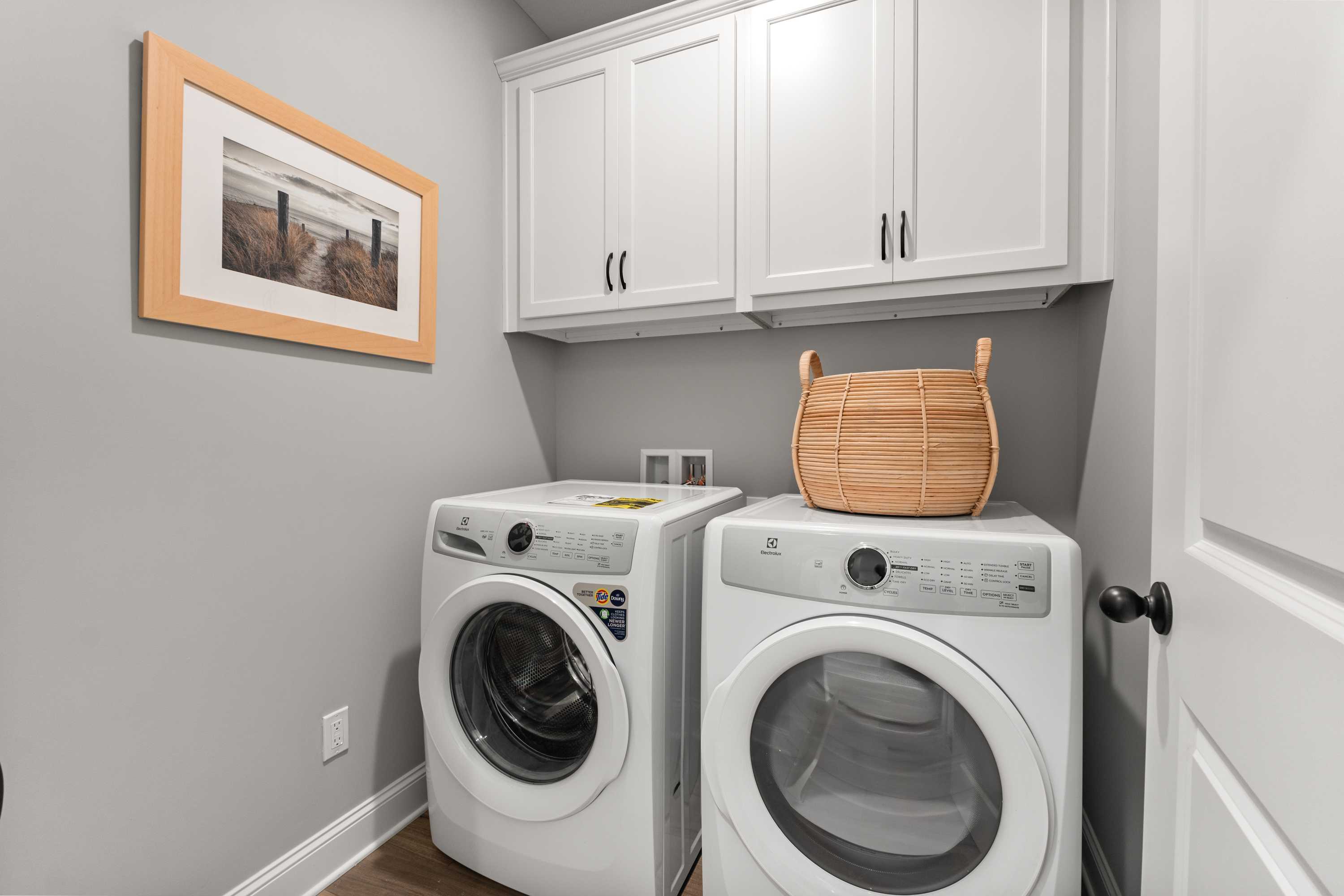 Spacious laundry room at Lynn Meadows in Meridianville, Alabama with white washer dryer, cabinets, and wicker basket