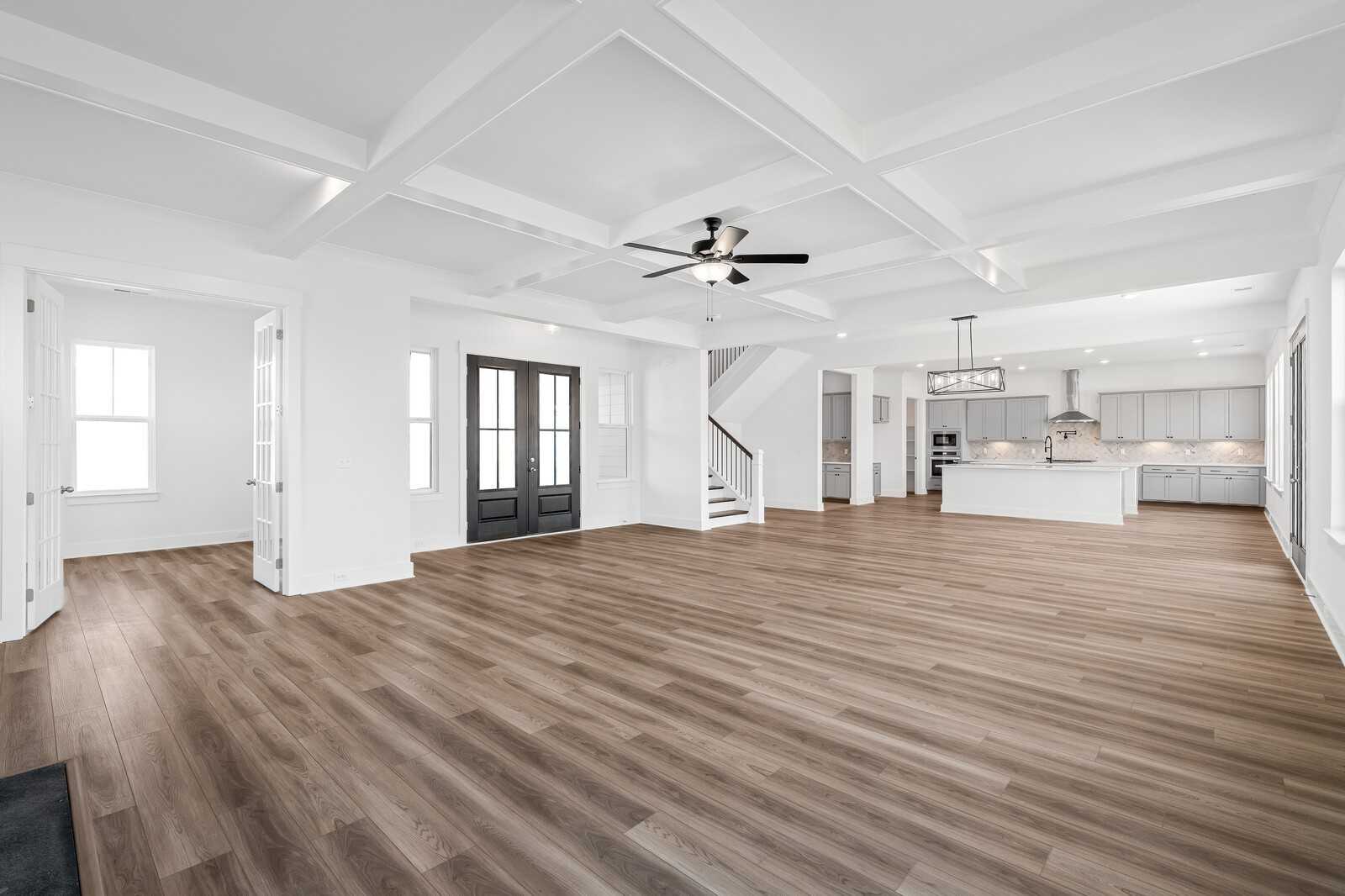 Grand foyer with coffered ceiling, chandelier, ceiling fan, open staircase, and adjacent kitchen in The Alston A by Davidson Homes, Murfreesboro, TN