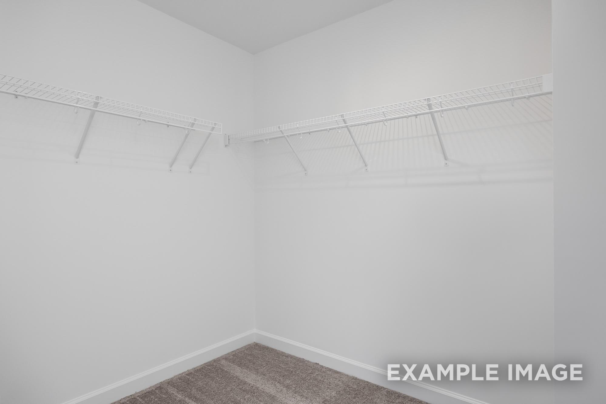 Spacious walk-in closet in The Cypress C II master suite with white wire shelving and hanging rods