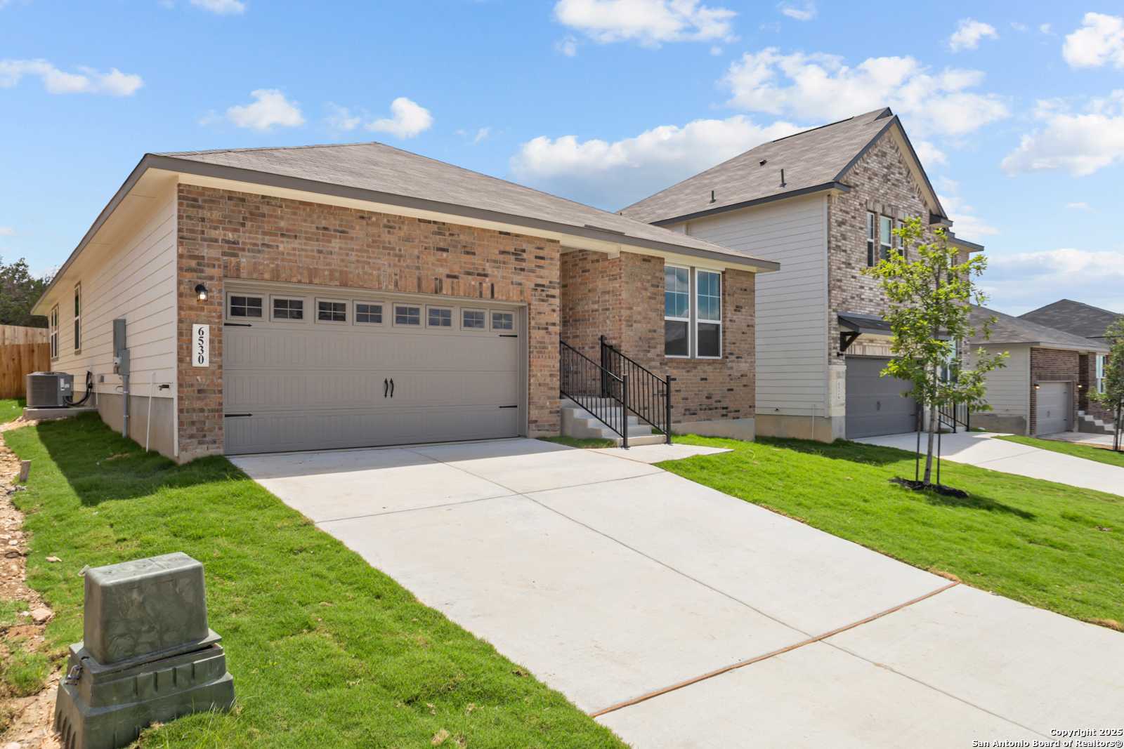 Modern 1-story brick and siding home with 2-car gray garage, driveway, green lawn in Royal Crest, San Antonio, Texas - Davidson Homes The Daphne G