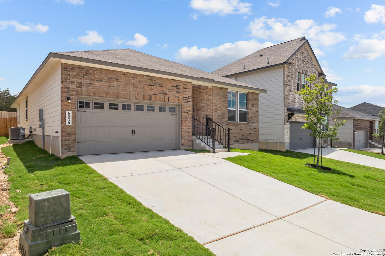 Modern 1-story brick and siding home with 2-car gray garage, driveway, green lawn in Royal Crest, San Antonio, Texas - Davidson Homes The Daphne G
