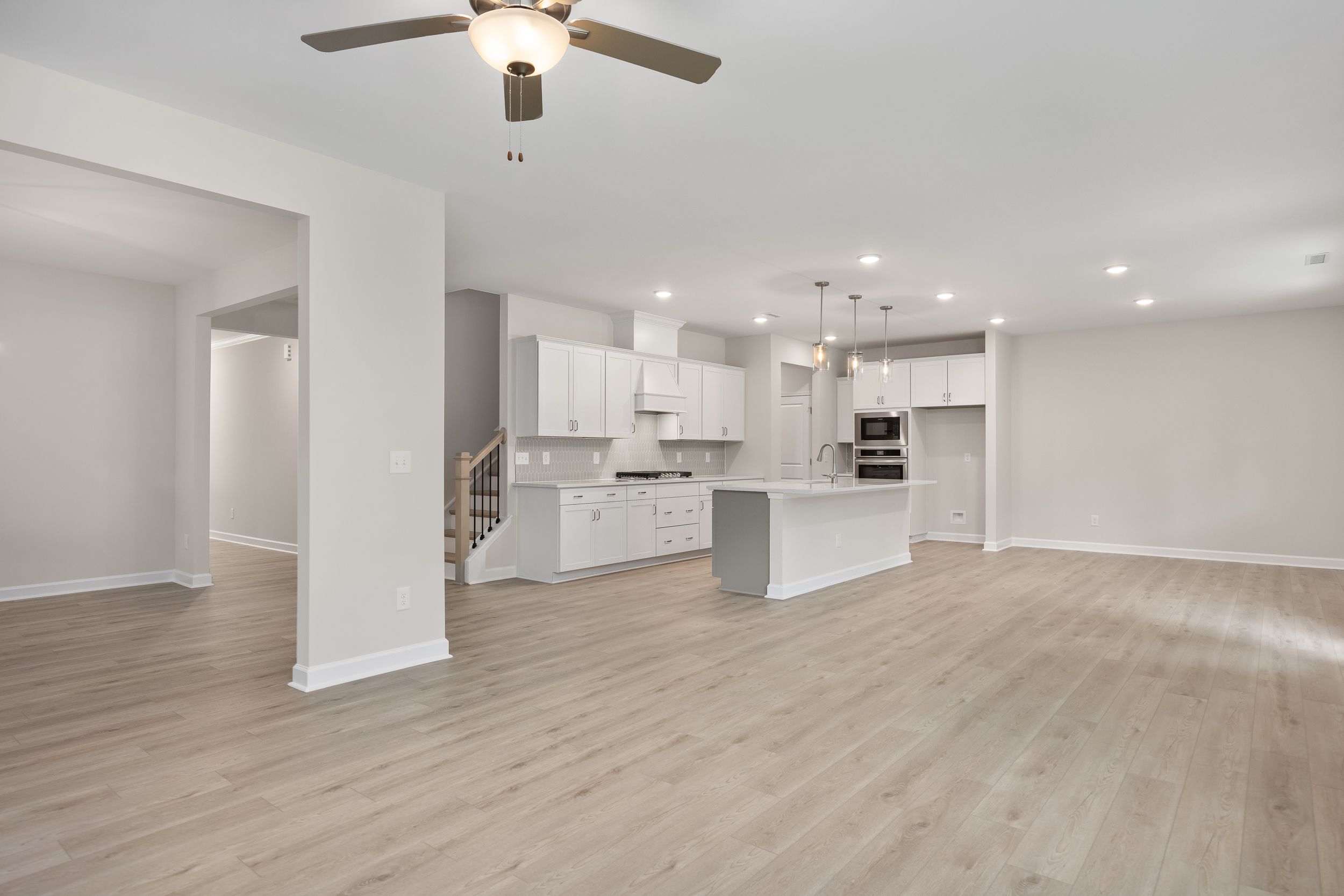 Spacious Beech A kitchen by Davidson Homes featuring white cabinetry, large central island with sink, stainless appliances, and open layout