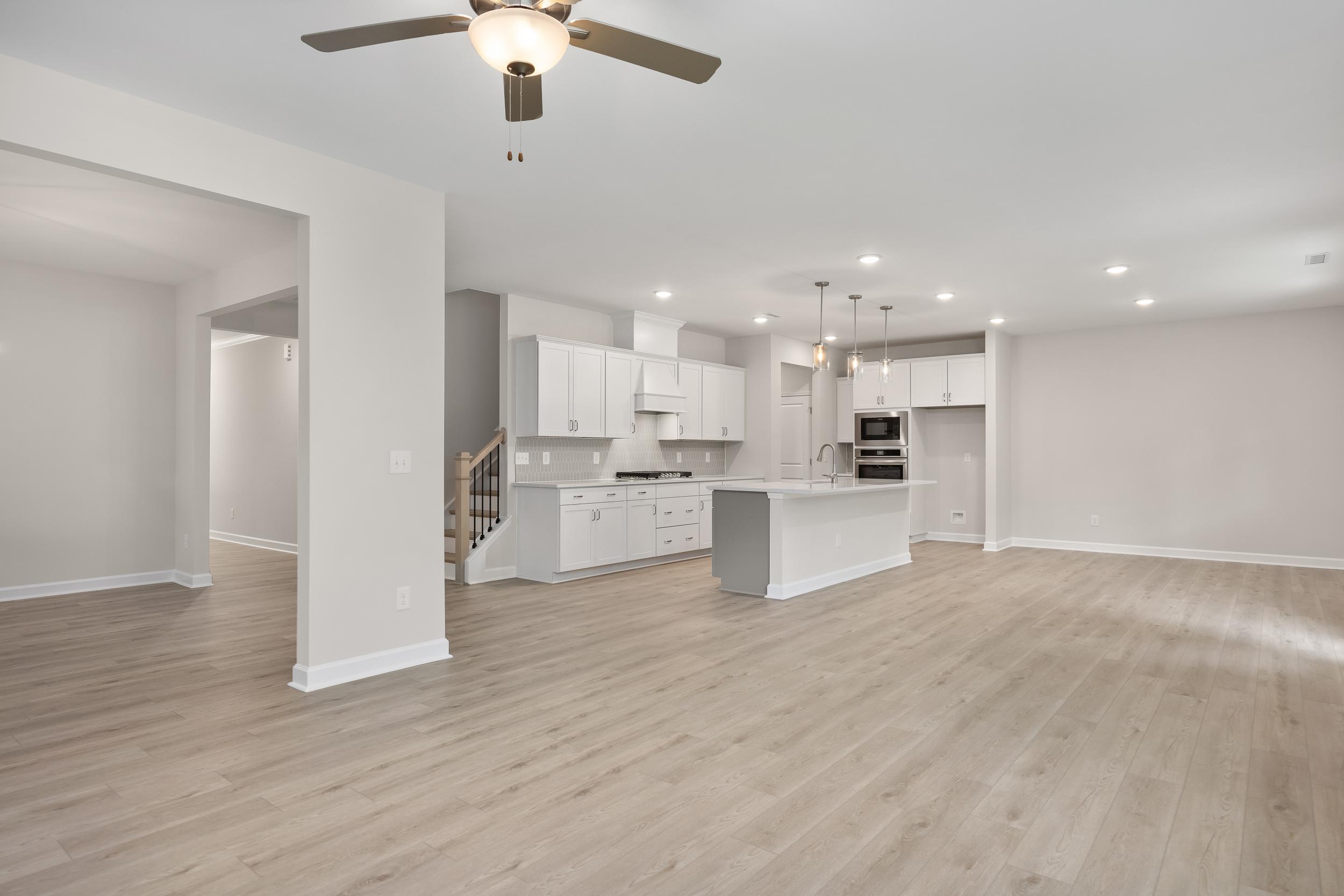 Spacious Beech A kitchen by Davidson Homes featuring white cabinetry, large central island with sink, stainless appliances, and open layout