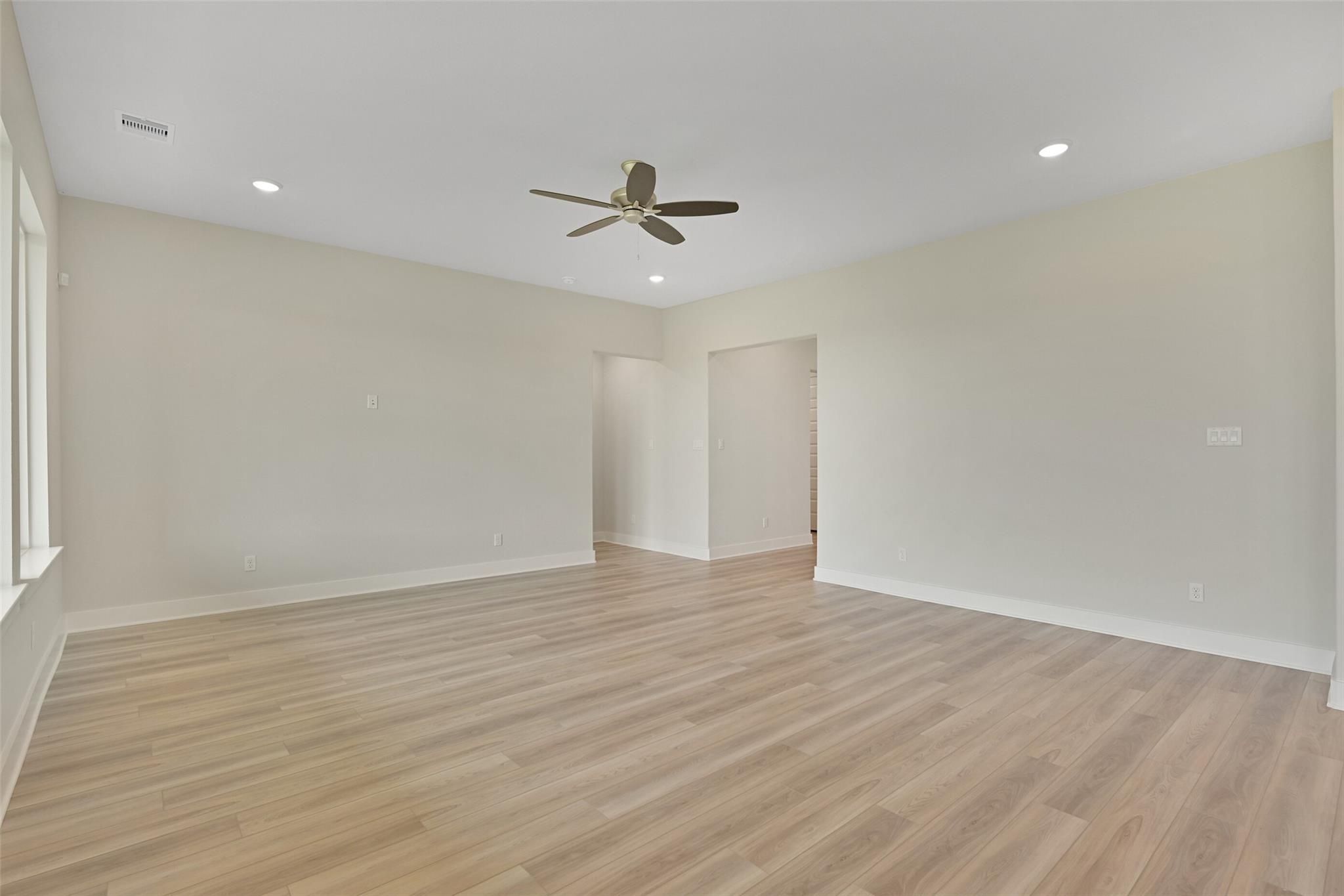 Spacious living room with ceiling fan, beige walls, and hardwood floors in Davidson Homes The Edward A, Lago Mar, Texas City