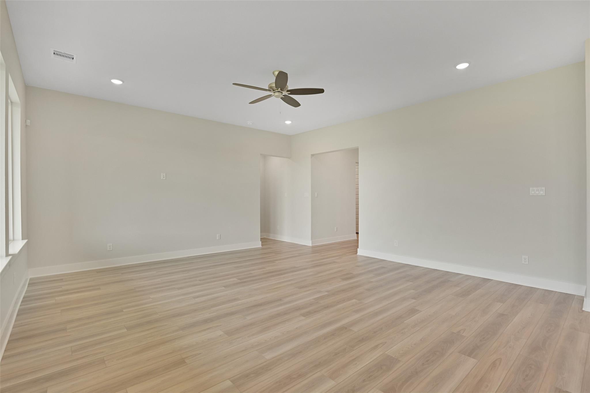 Spacious living room with ceiling fan, beige walls, and hardwood floors in Davidson Homes The Edward A, Lago Mar, Texas City