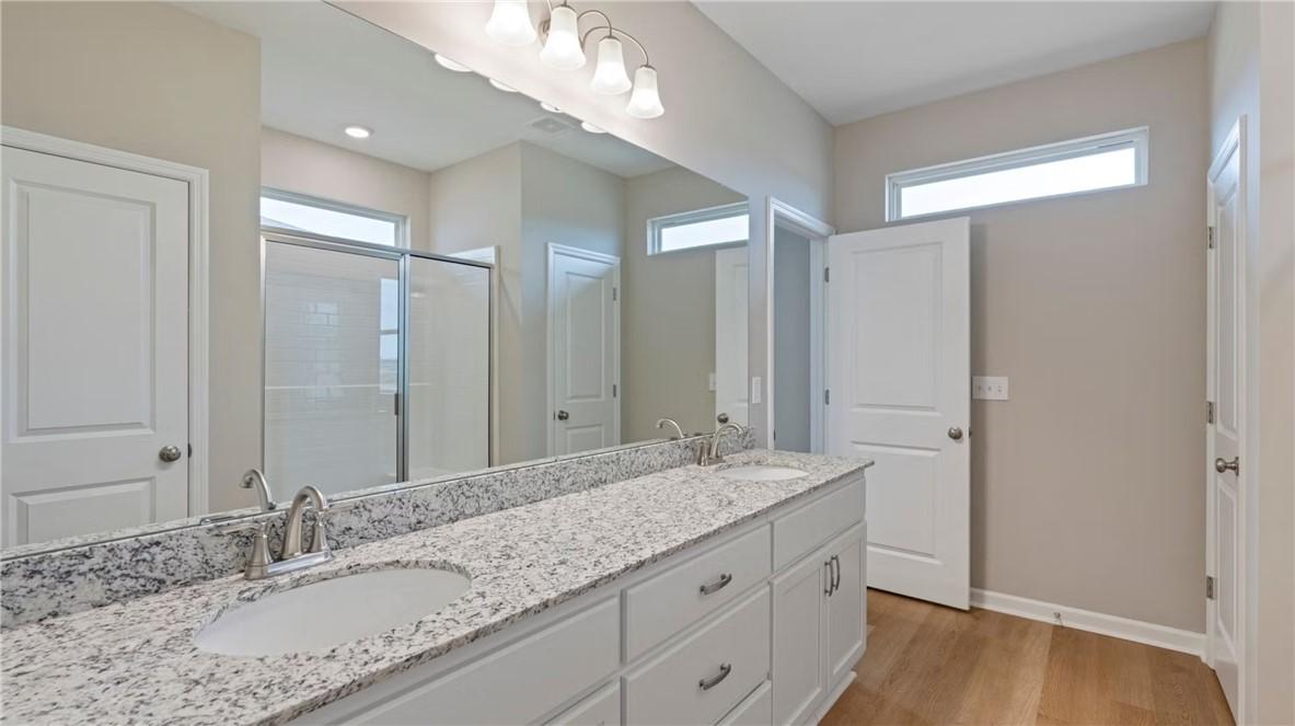 Elegant master bathroom with double vanity, granite counters, frameless shower in The Stella D by Evermore Homes, Cusseta, Alabama