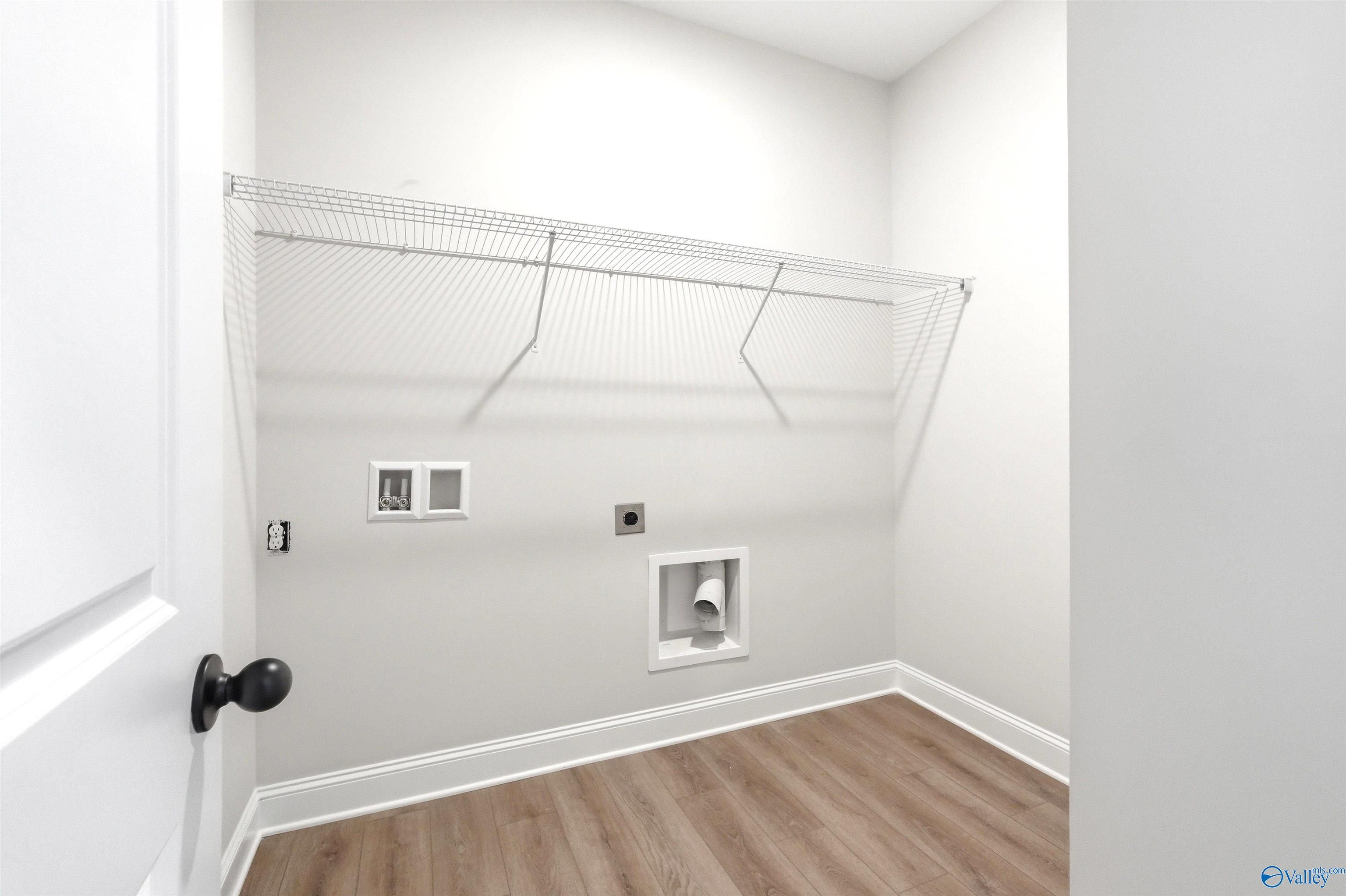 Laundry room with wire shelving and utility hookups in The Daphne F floor plan at Berry Cove in New Market, Alabama.