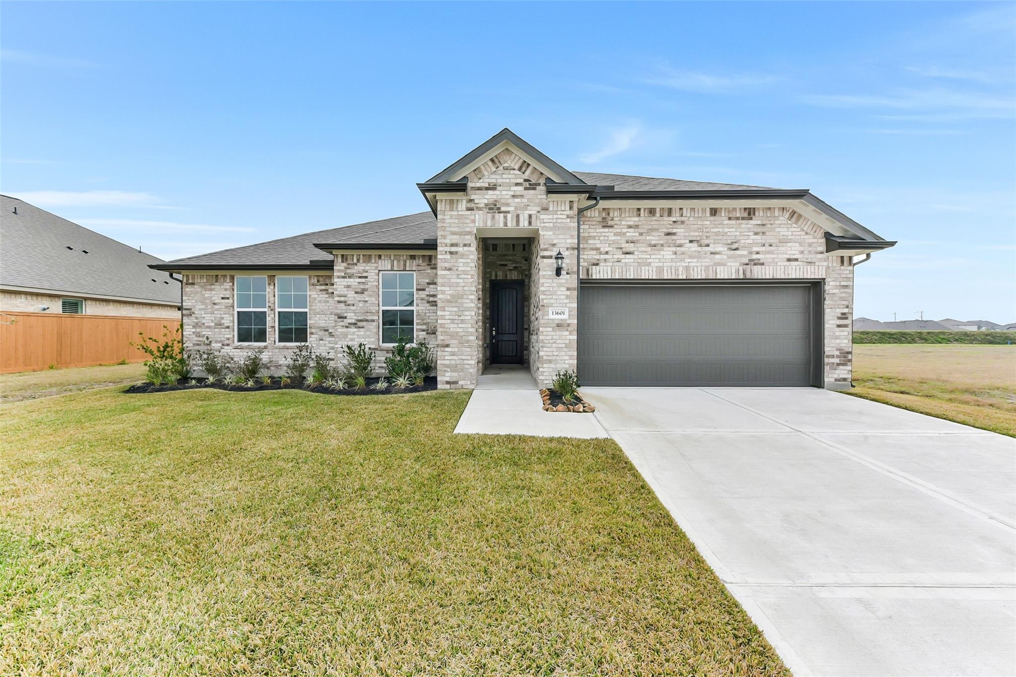 Modern white brick single-story home with 2-car garage, driveway, and landscaped lawn in Lago Mar, Texas City, Texas