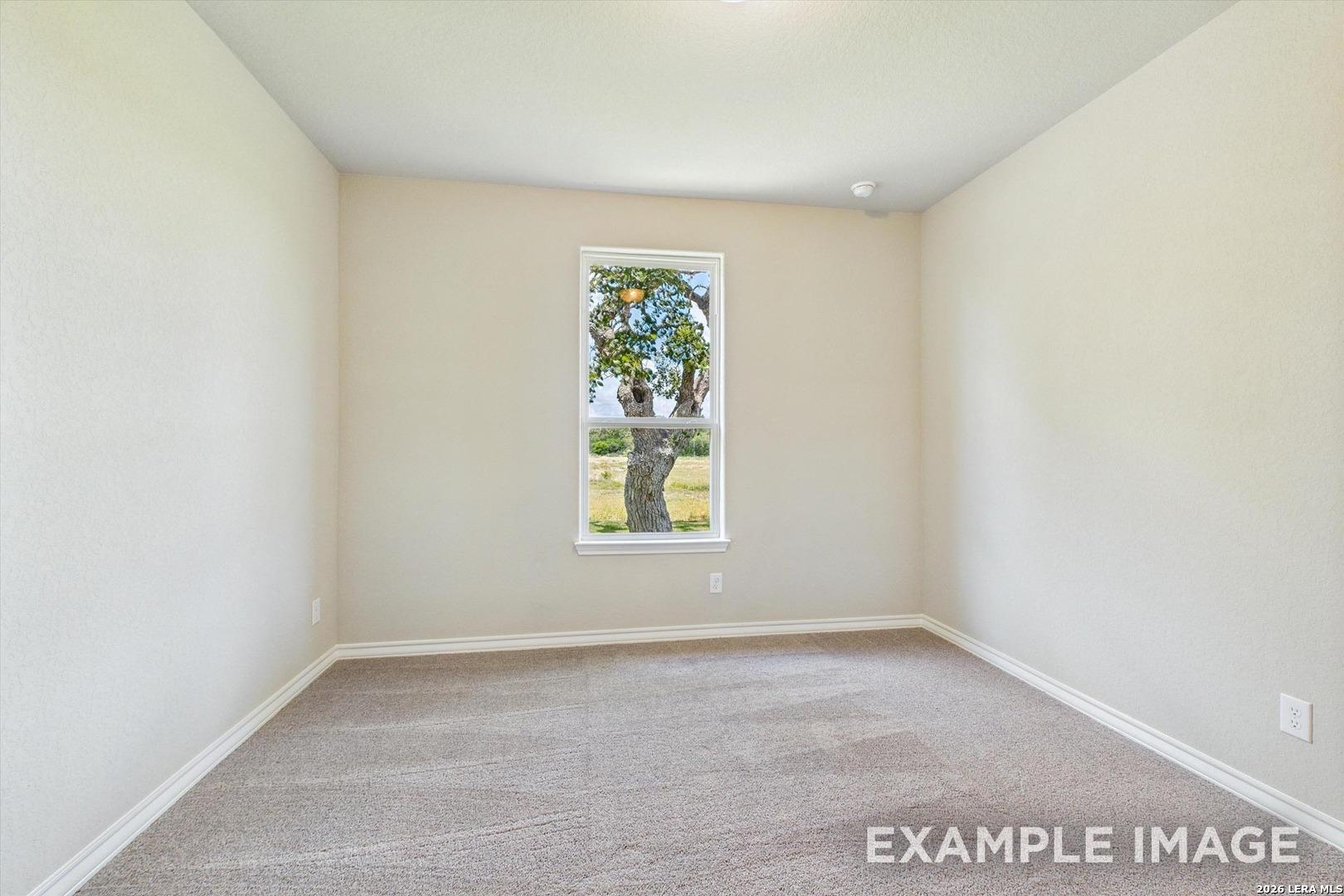 Neutral bedroom with carpet and scenic window view in The Foster F floor plan by Davidson Homes in Potranco Oaks.
