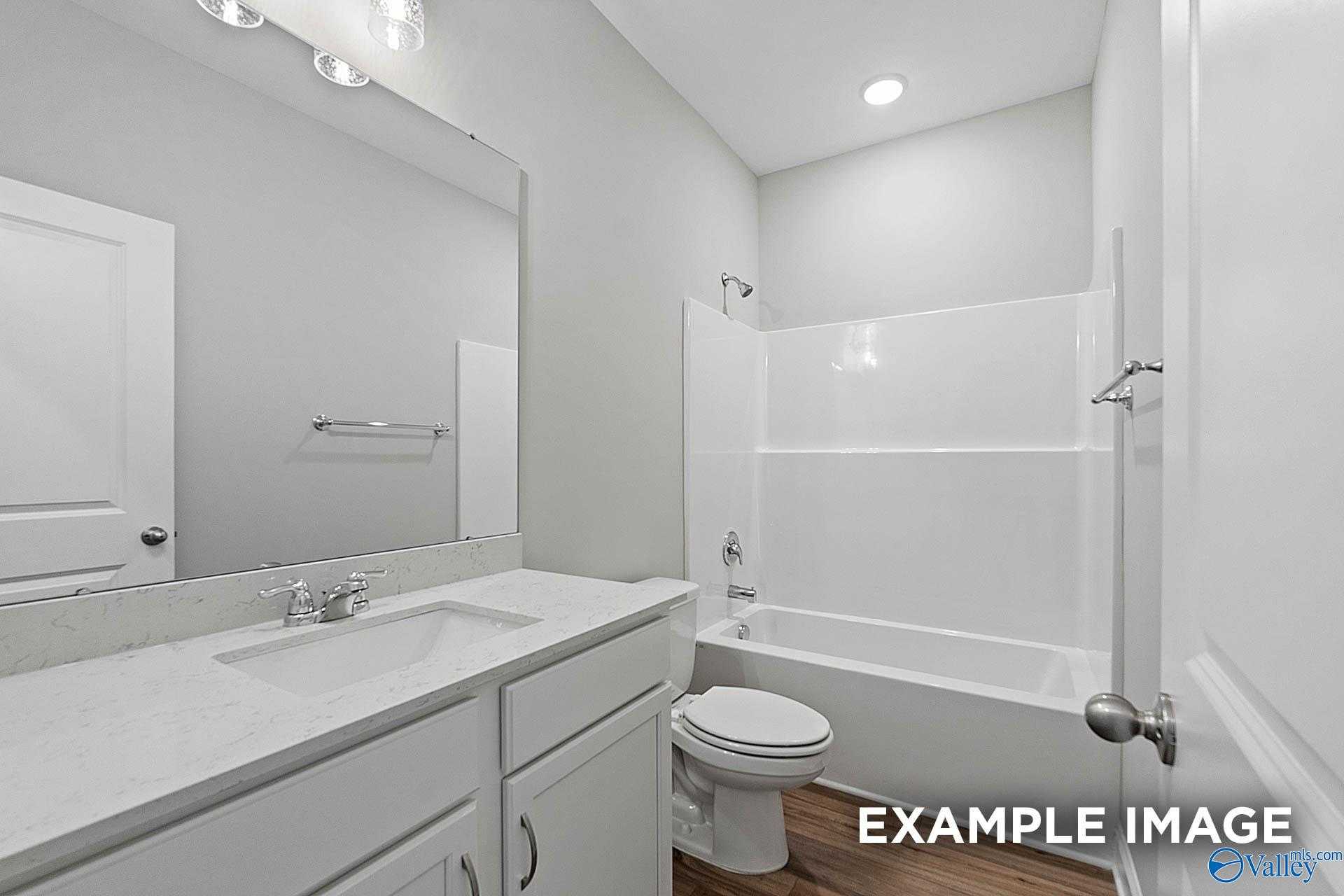 Bright bathroom with white vanity, soaking tub-shower combo, and toilet in Davidson Homes The Franklin E, Hazel Green, AL