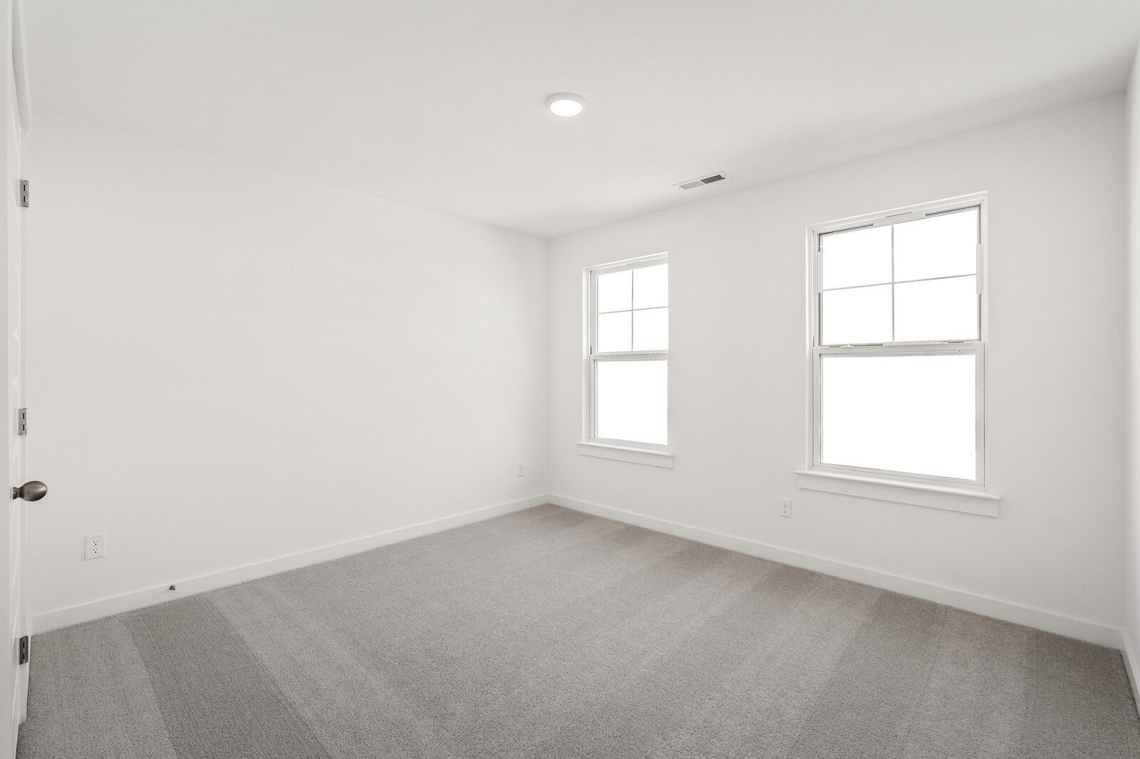 Bright empty secondary bedroom with white walls, plush carpet, and double windows in Davidson Homes The Ash A, Gallatin, TN