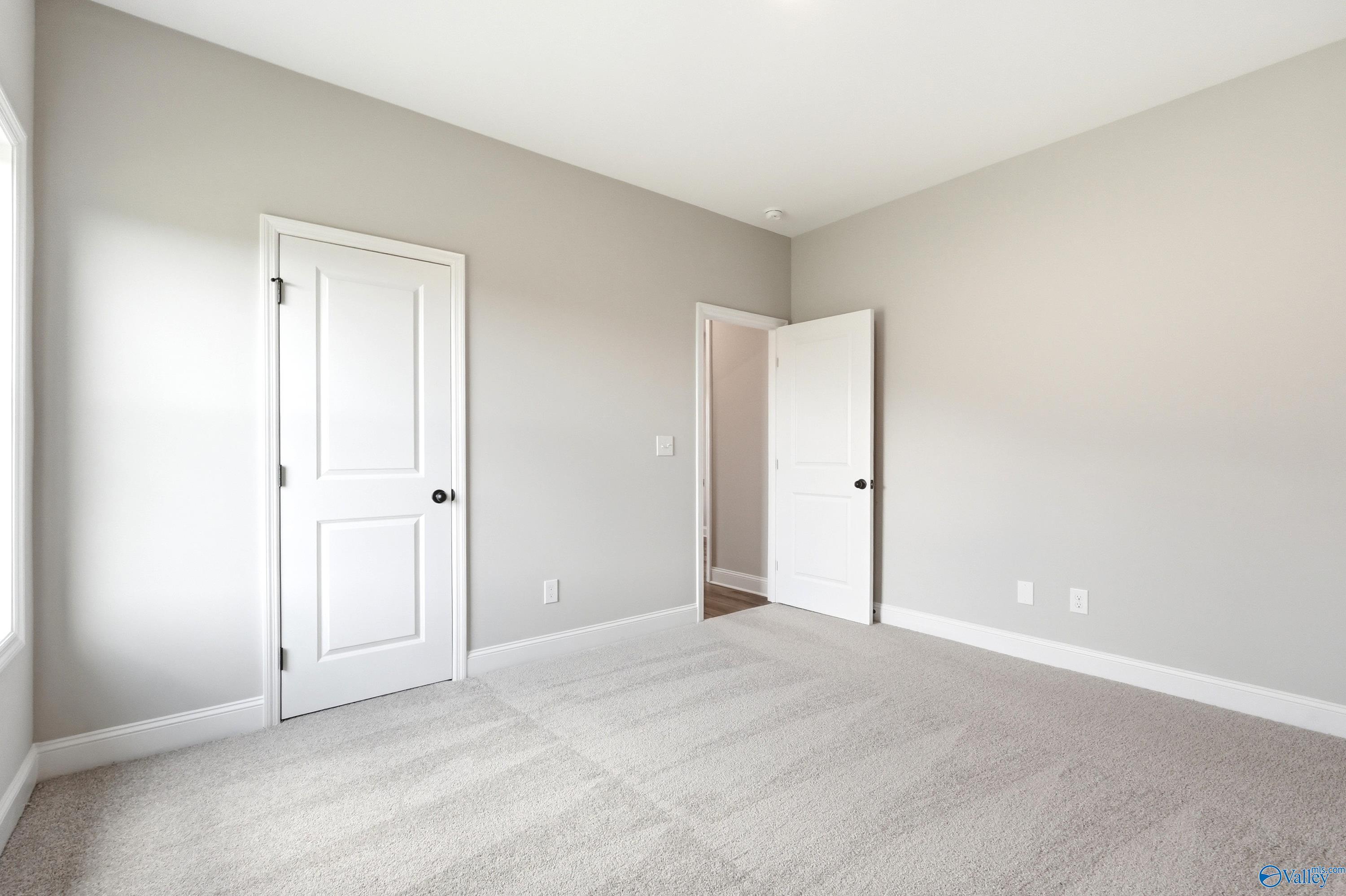 Bright, neutral-toned bedroom with plush carpet in The Daphne D floor plan by Davidson Homes in Creekside, Harvest, AL.