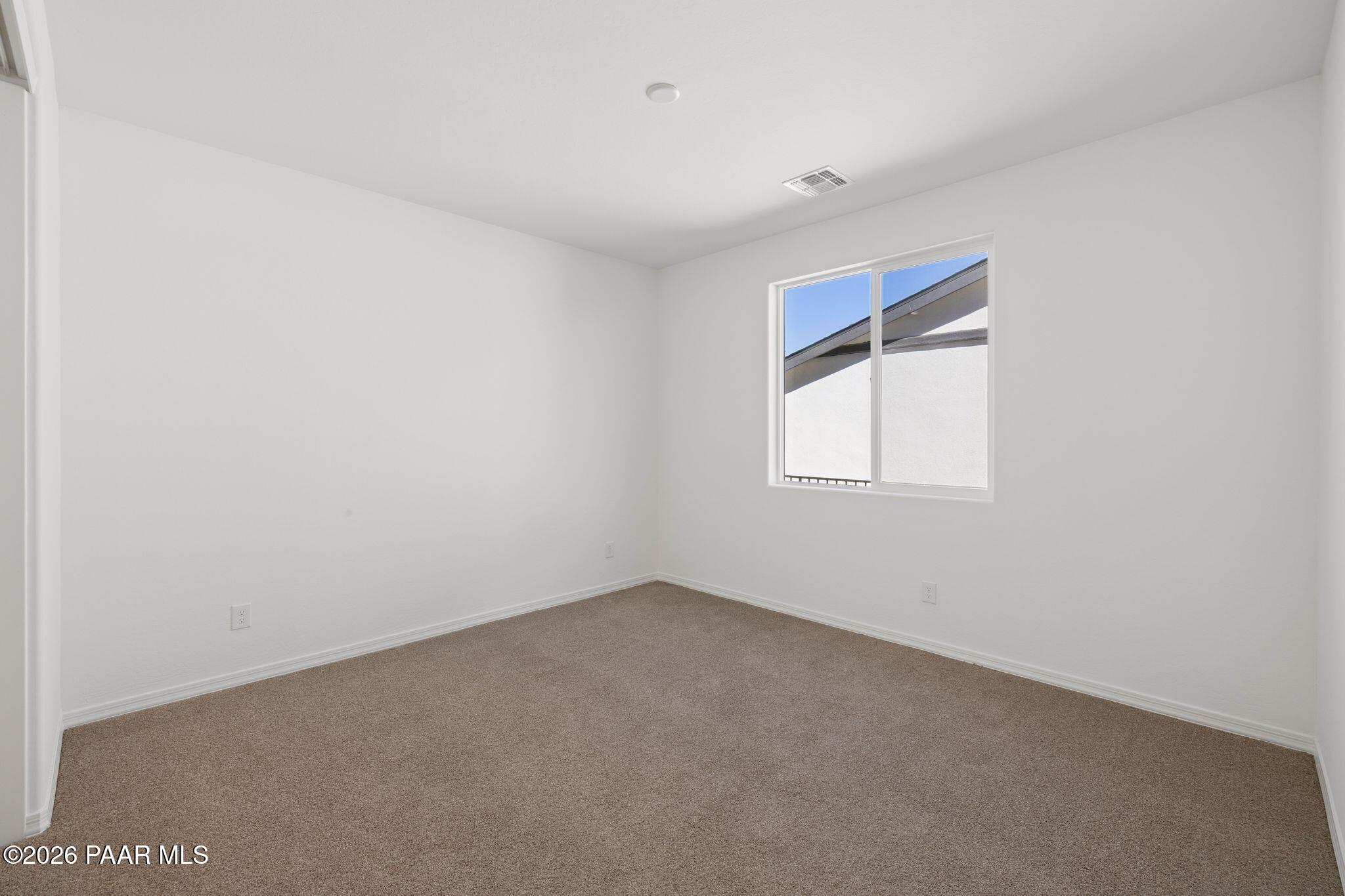 Bright empty bedroom featuring white walls, large window, and beige carpet in Davidson Homes The Monarch A, Prescott AZ