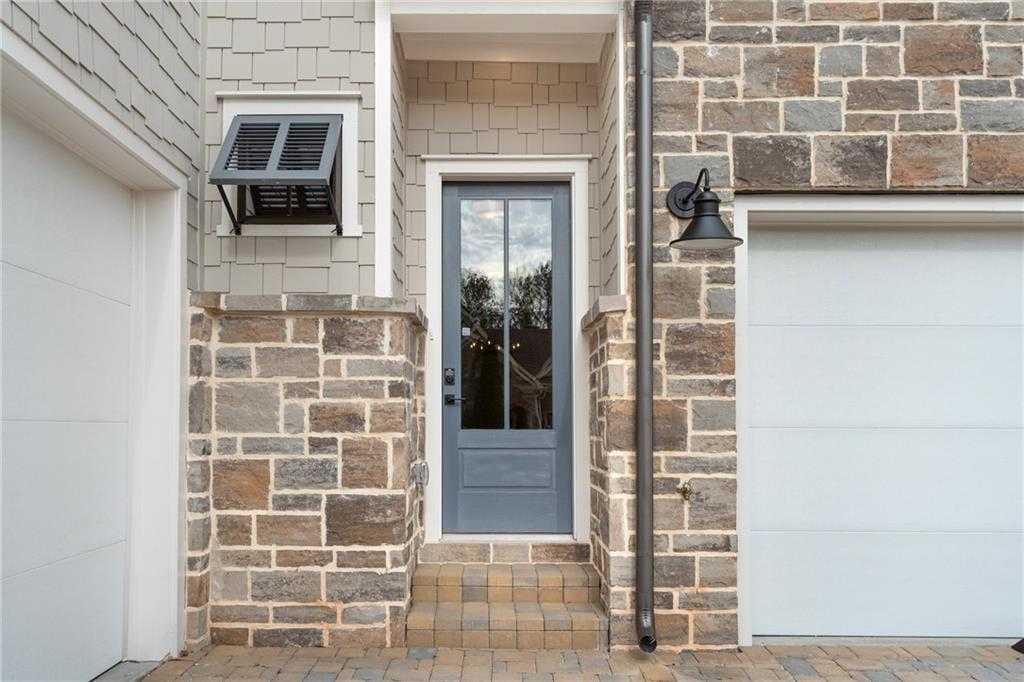 Elegant blue front door with glass panels, stone pillars, and 3-car garage in Davidson Homes The Seaside B, Woodstock, Georgia