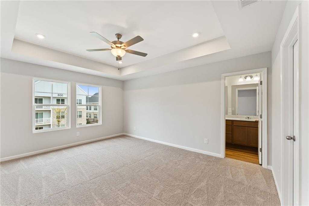 Spacious carpeted bedroom with ceiling fan, large windows, and en-suite bath in Davidson Homes Monroe A, Emerson, Georgia