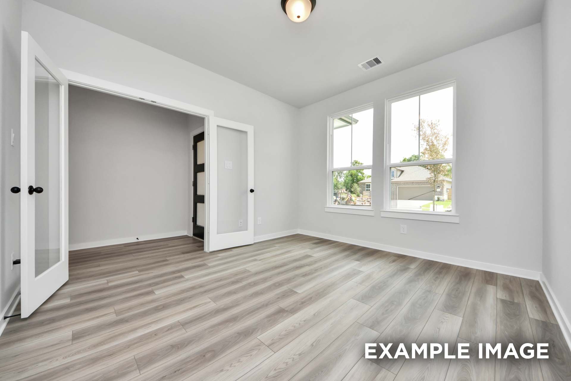 Bright flex room in The Sorrento home design featuring elegant French doors, light wood flooring, and large windows.