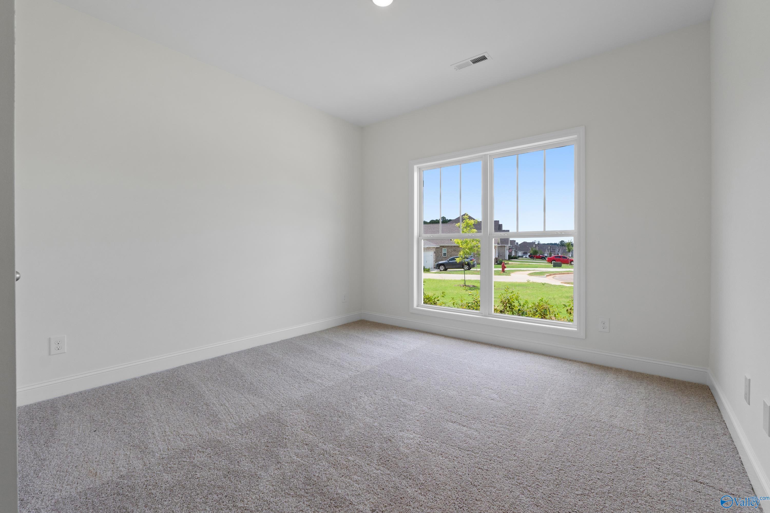 Spacious, light-filled bedroom with plush carpeting in The Everett B floor plan at The Meadows, Athens, Alabama.