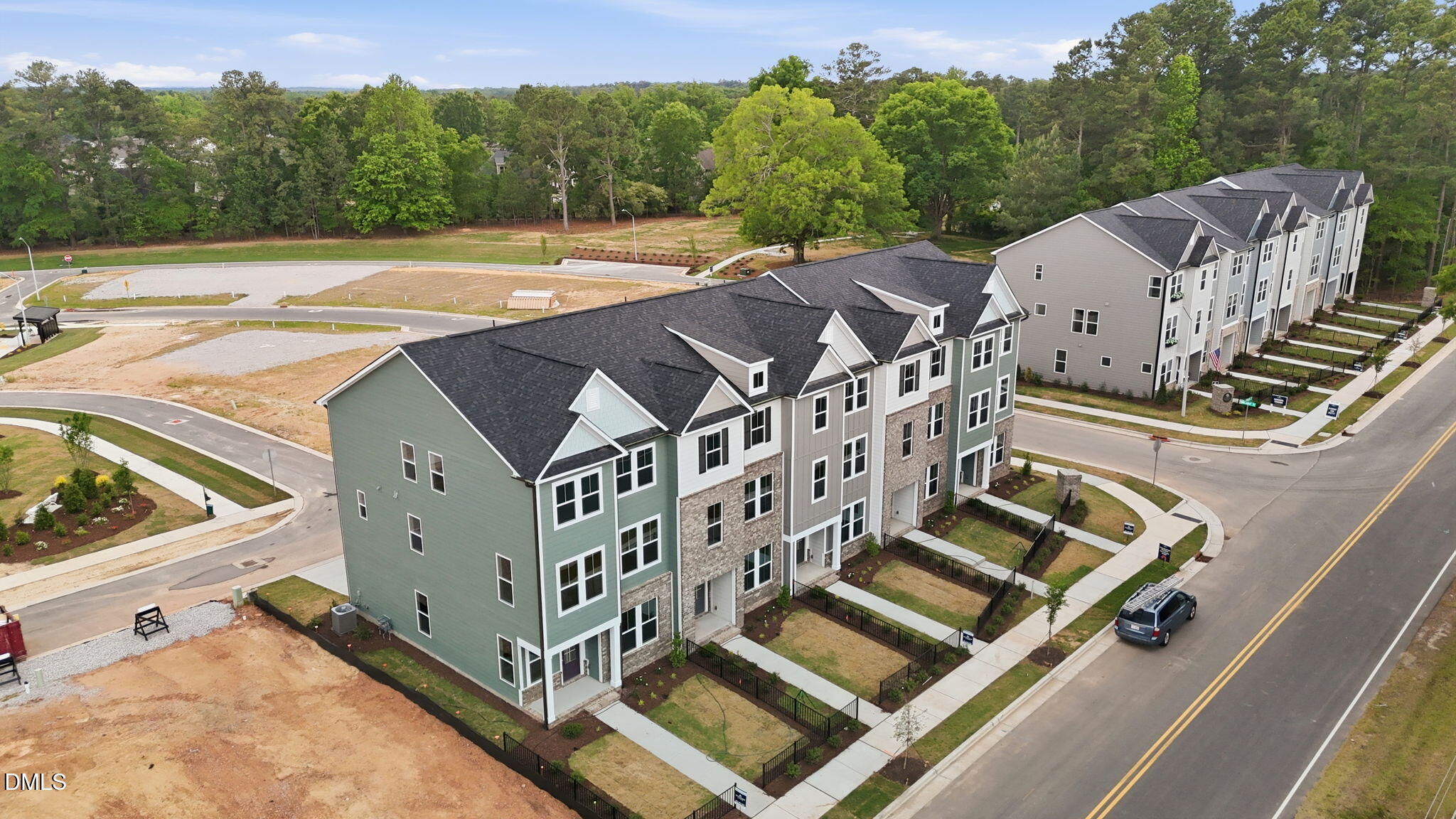 Modern 3-story townhomes with gray siding, black roofs, and garages in Davidson Homes The Mitchell Exterior, Camden Park, Knightdale, NC